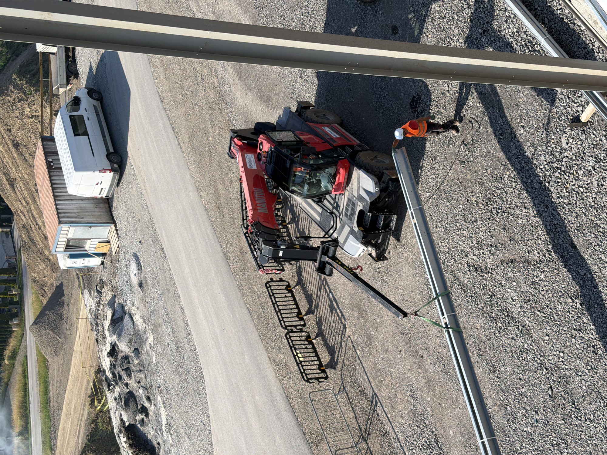 Hard-hatted worker handles wiring at a sunny Stróża construction site.