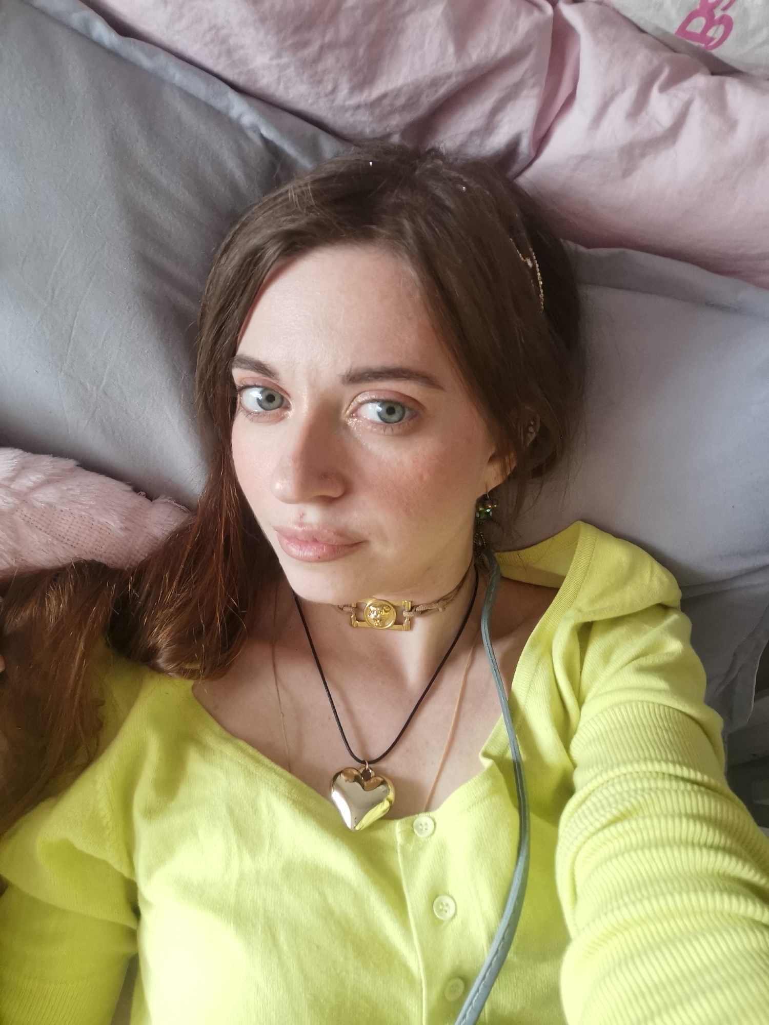 Woman in yellow cardigan rests on bed, location unknown