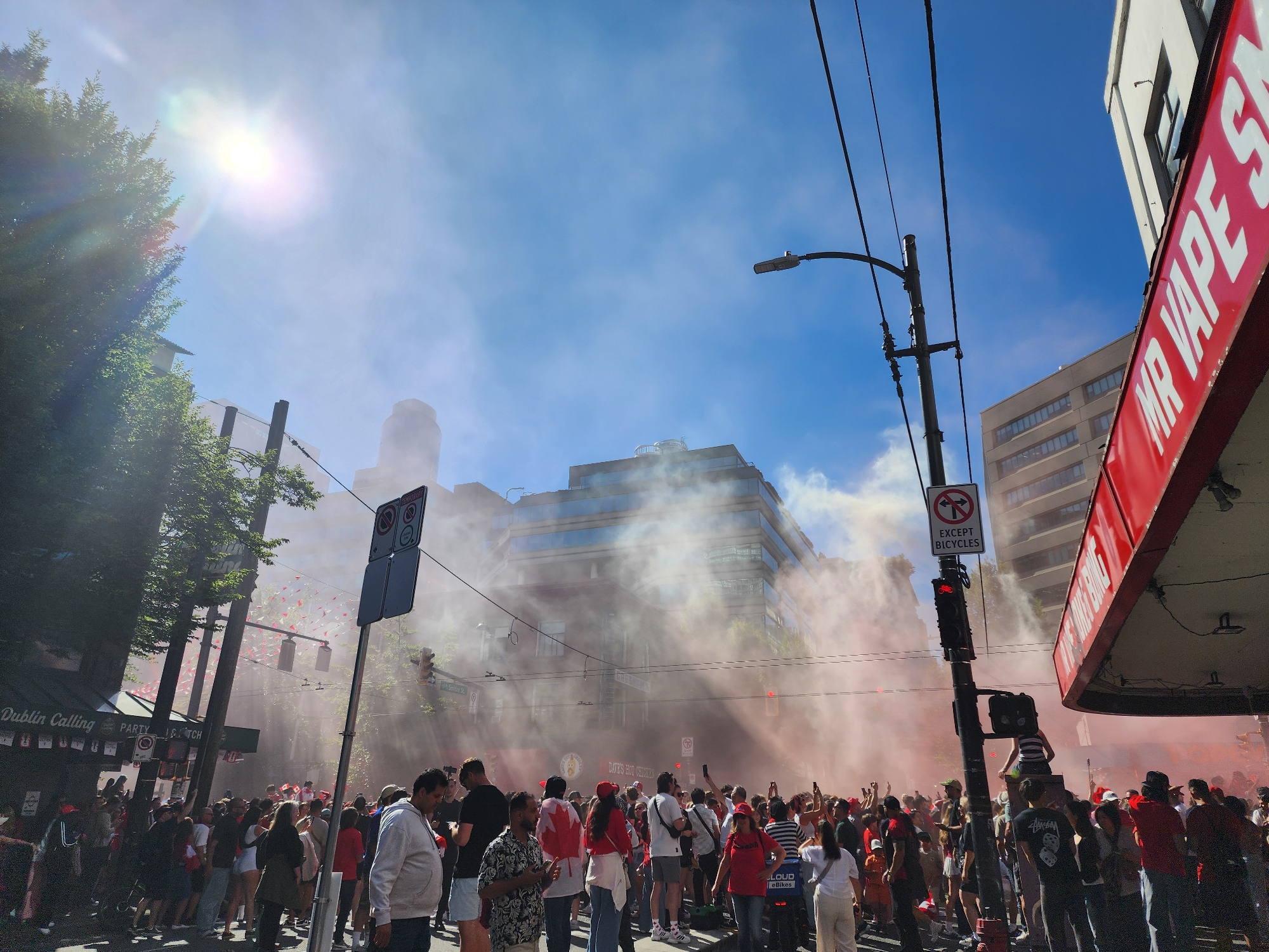 Canada Day street celebration with flags, crowds, and pink smoke