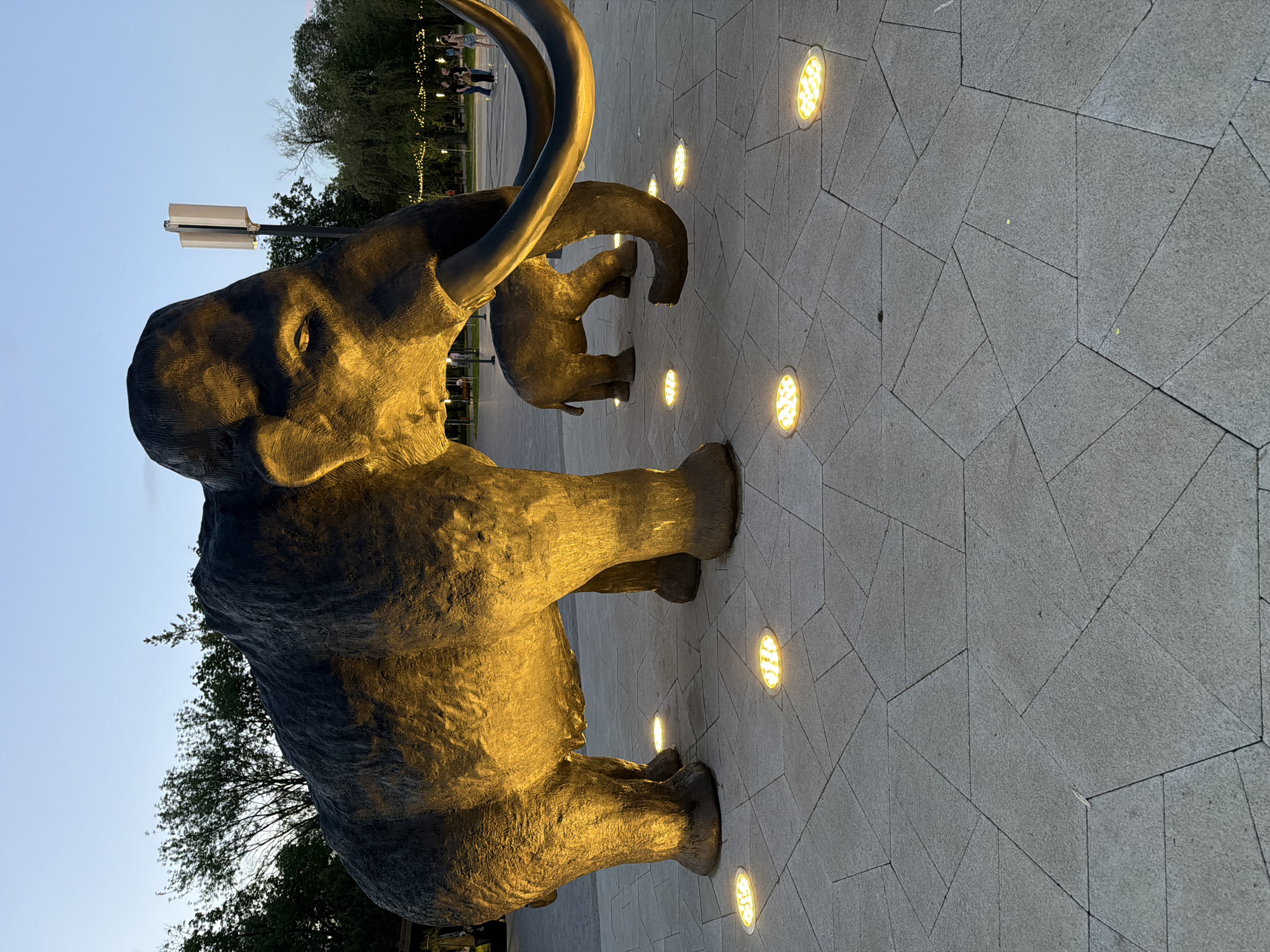 Evening park visit features illuminated mammoth sculptures and sunset scenes