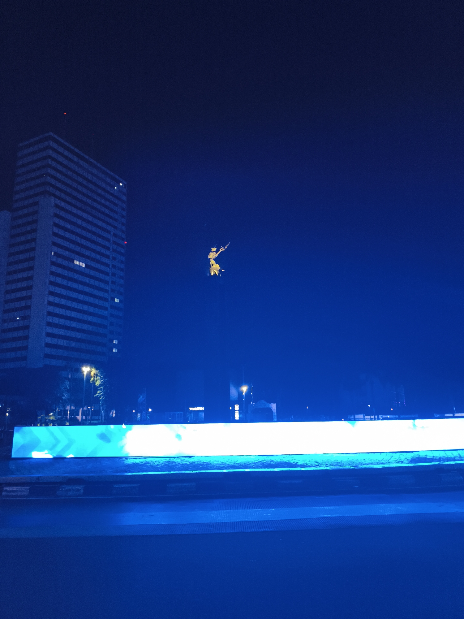 Nighttime urban traffic flows past illuminated commercial buildings