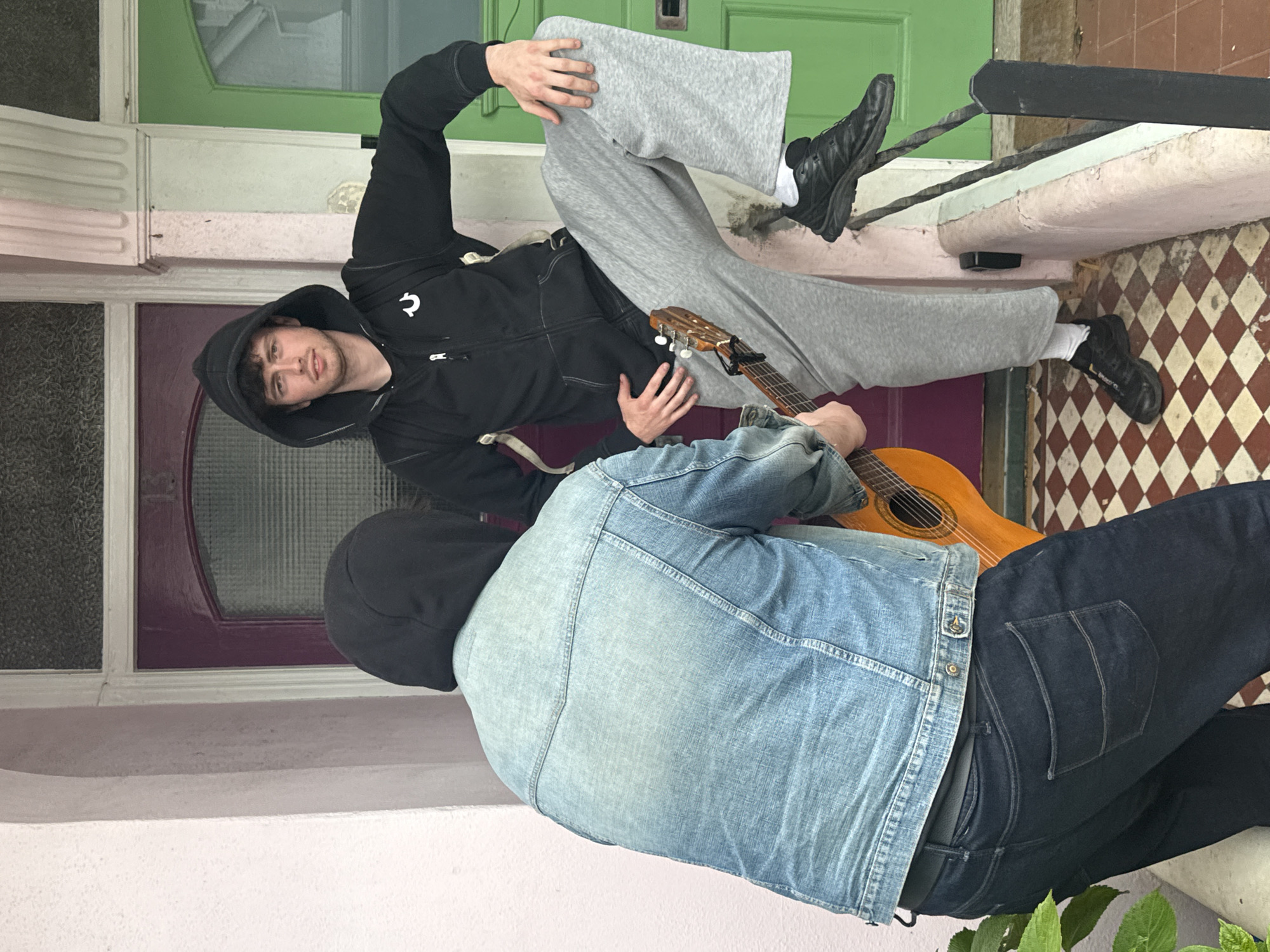 Two people with guitar sit on Brighton building steps