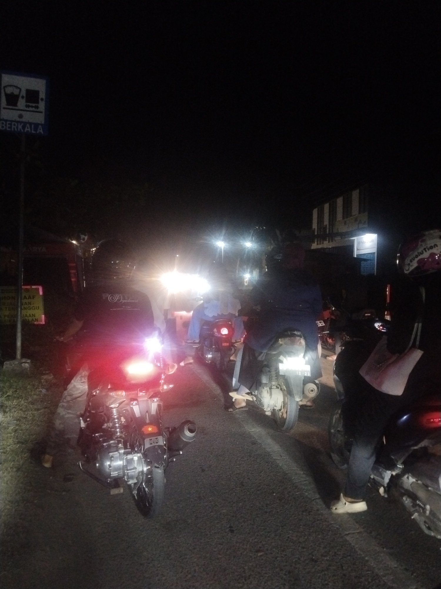 Motorcycles line up on congested Lhokseumawe street at night