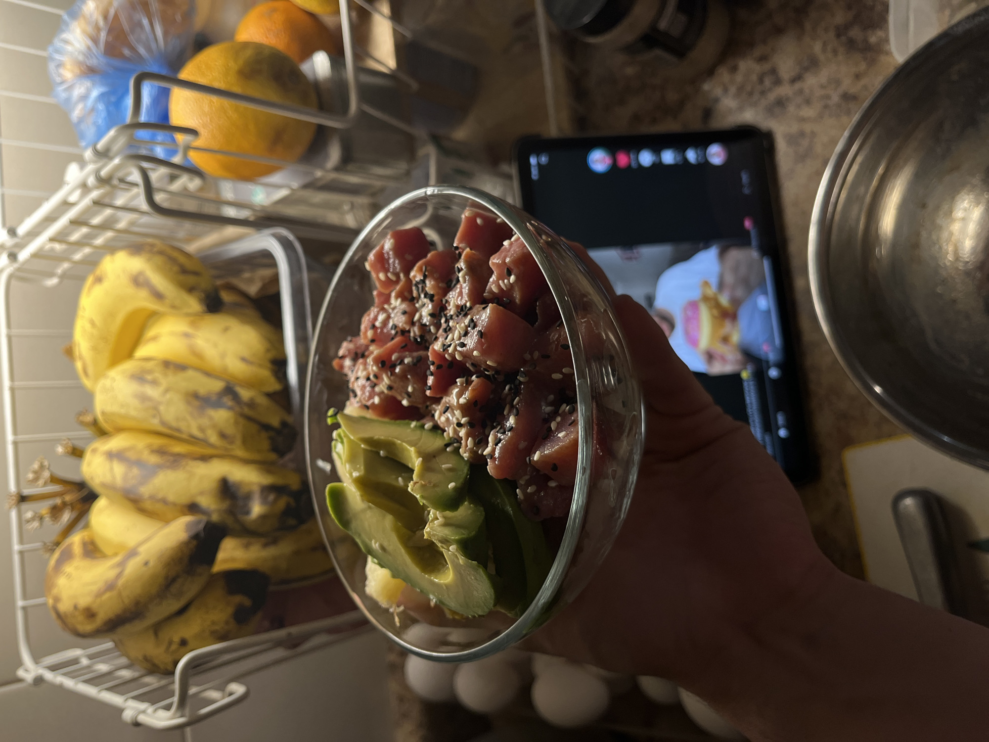 Poke bowl with fresh toppings, fruit basket in the background