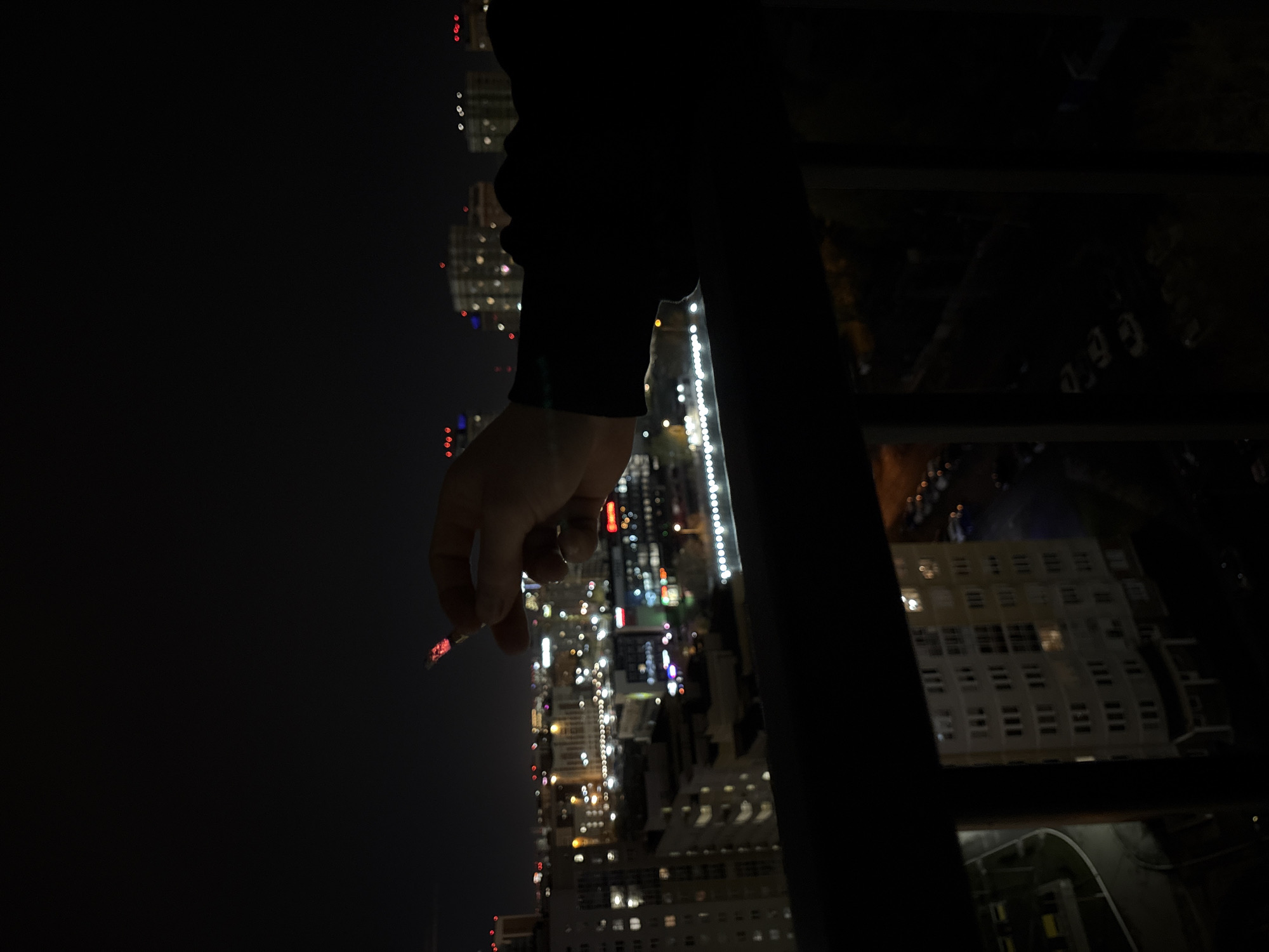 Person smokes overlooking Yekaterinburg cityscape at night