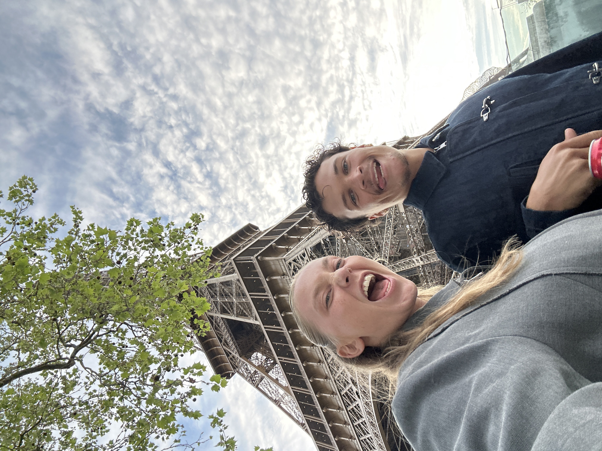 Tourist photographs Eiffel Tower under cloudy Paris skies