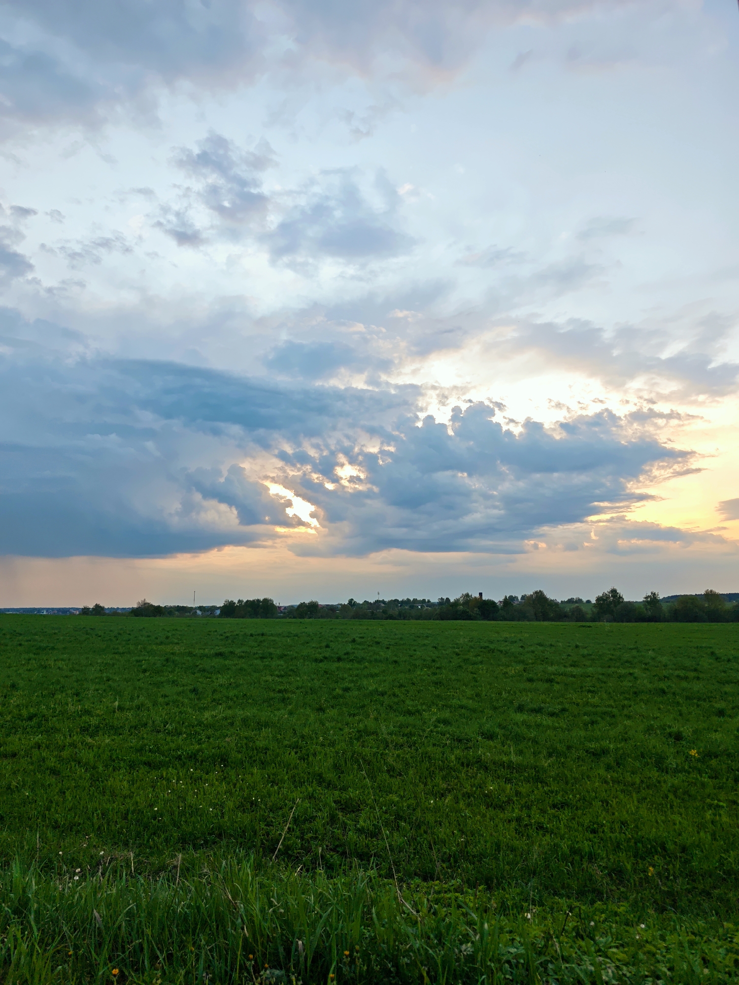 Sunlight breaks through clouds over green field in Yakhroma