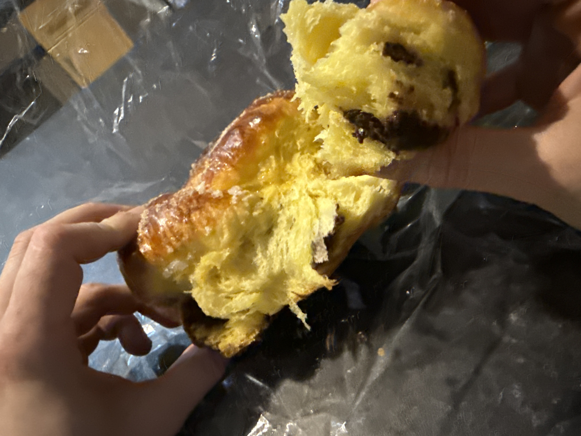 Person breaks open glazed pastry in Great Yarmouth