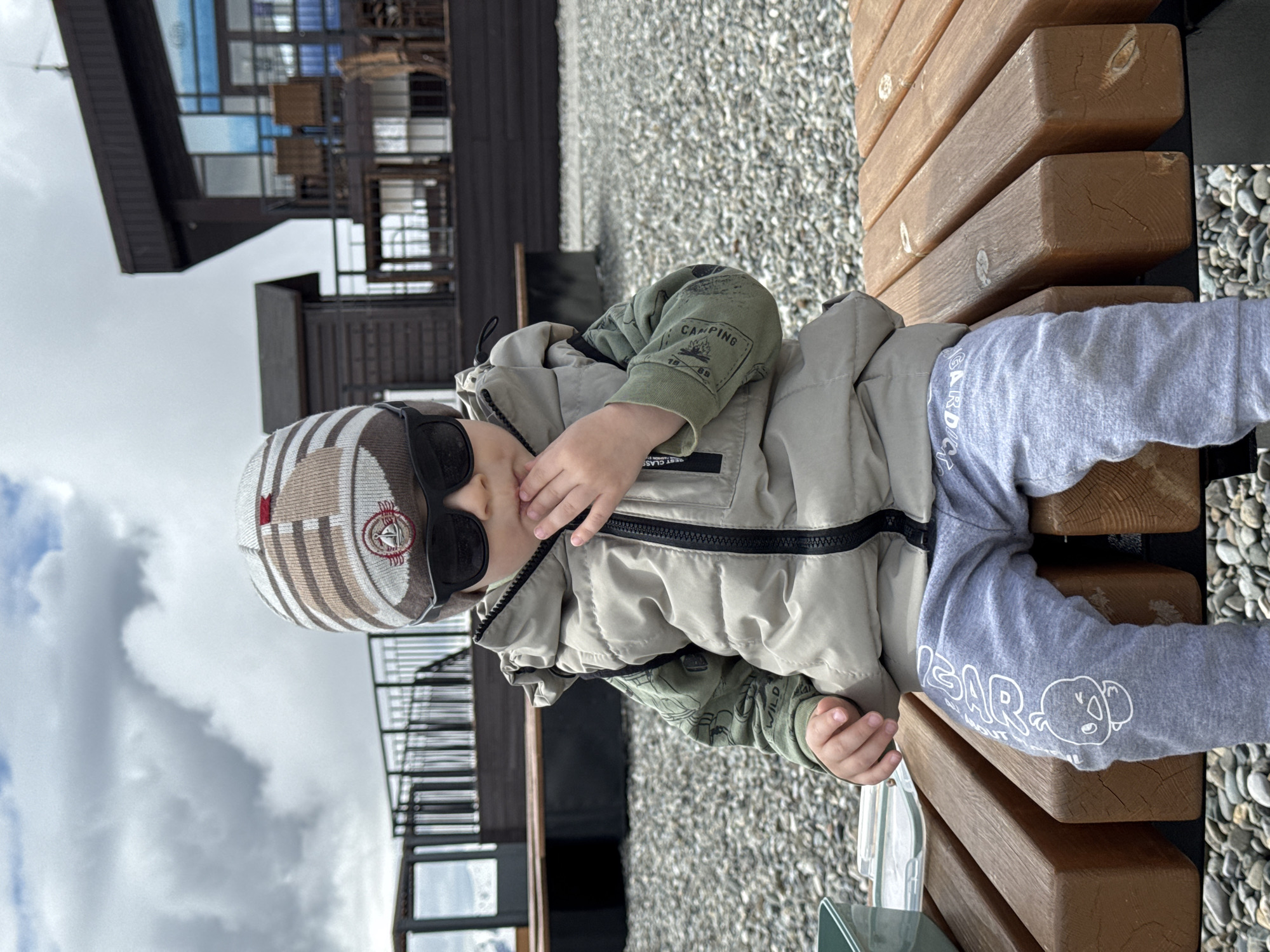 Toddler in sunglasses rests on wooden bench in Estosadok