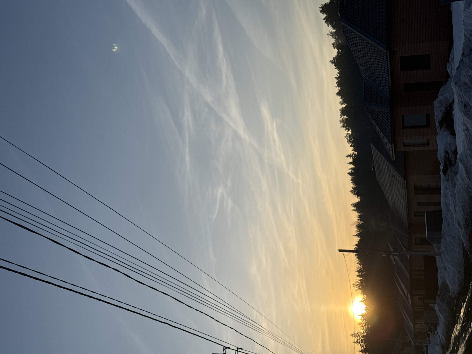 Sunrise observed in Chaikovsky, Russia with power lines, contrails