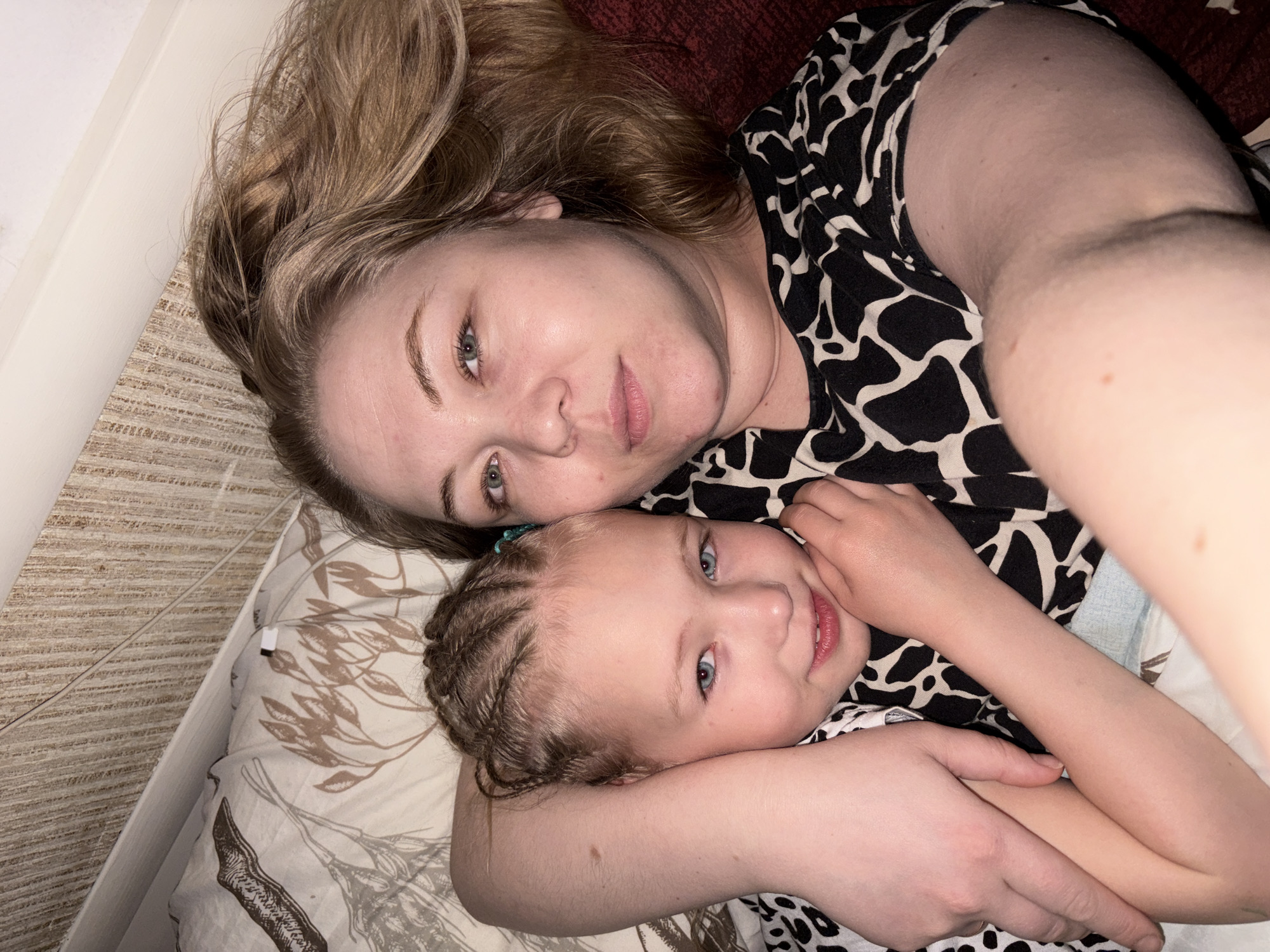Woman and child rest together on bed in Noviy