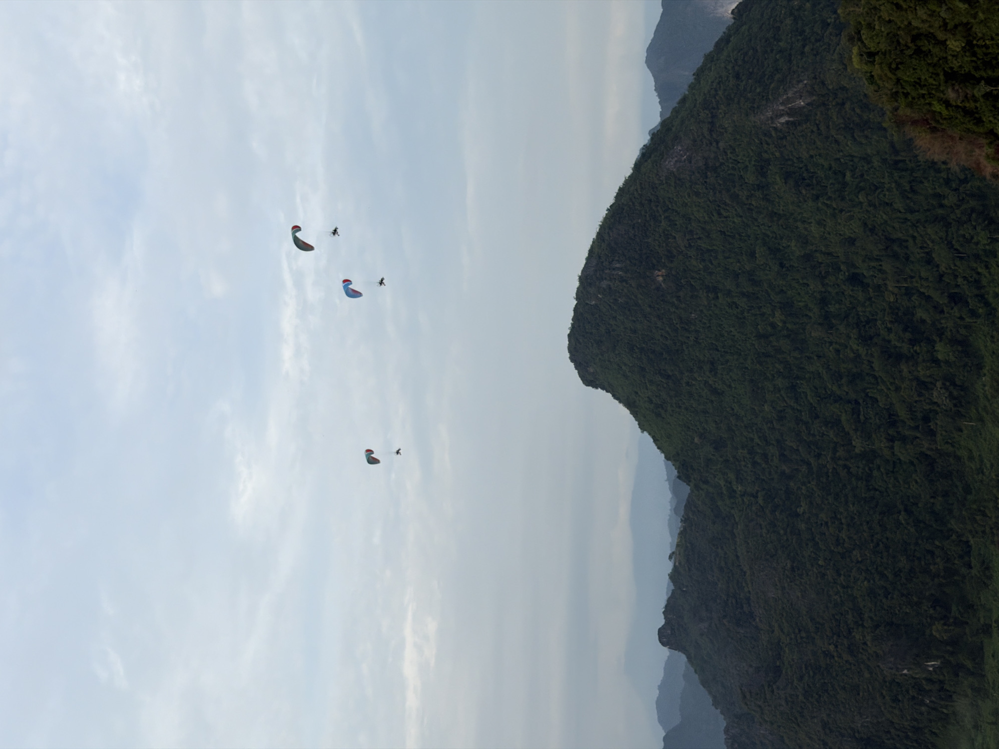 Paragliders soaring above Vang Vieng's mountain landscape