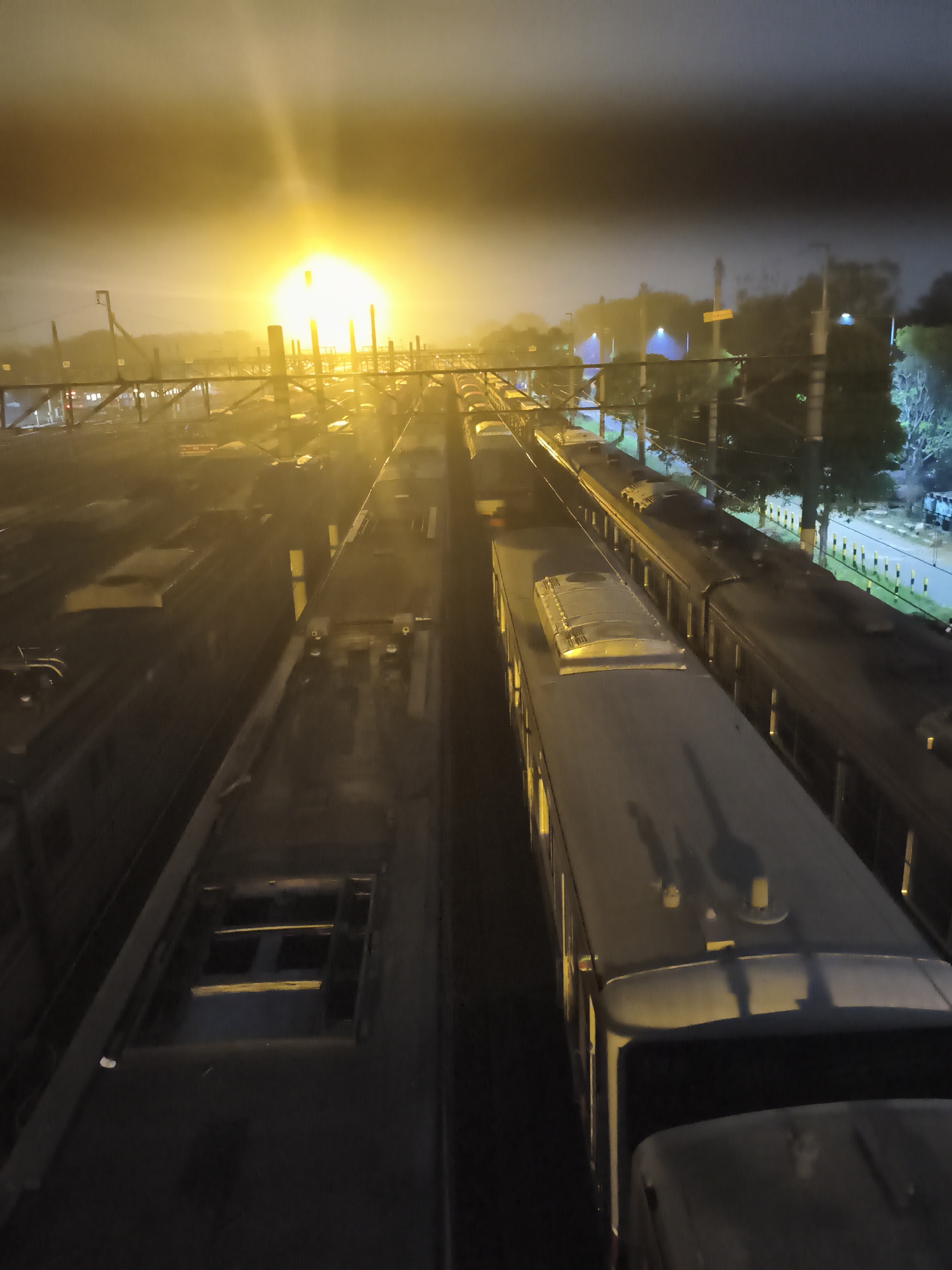Depok train yard at night, viewed through the fence