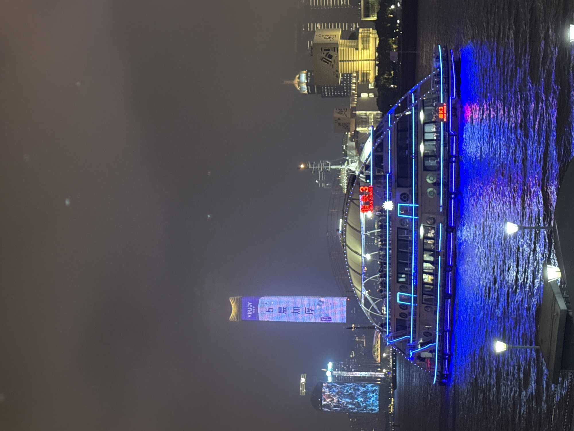 Woman overlooks illuminated tour boat on Shanghai's Huangpu River
