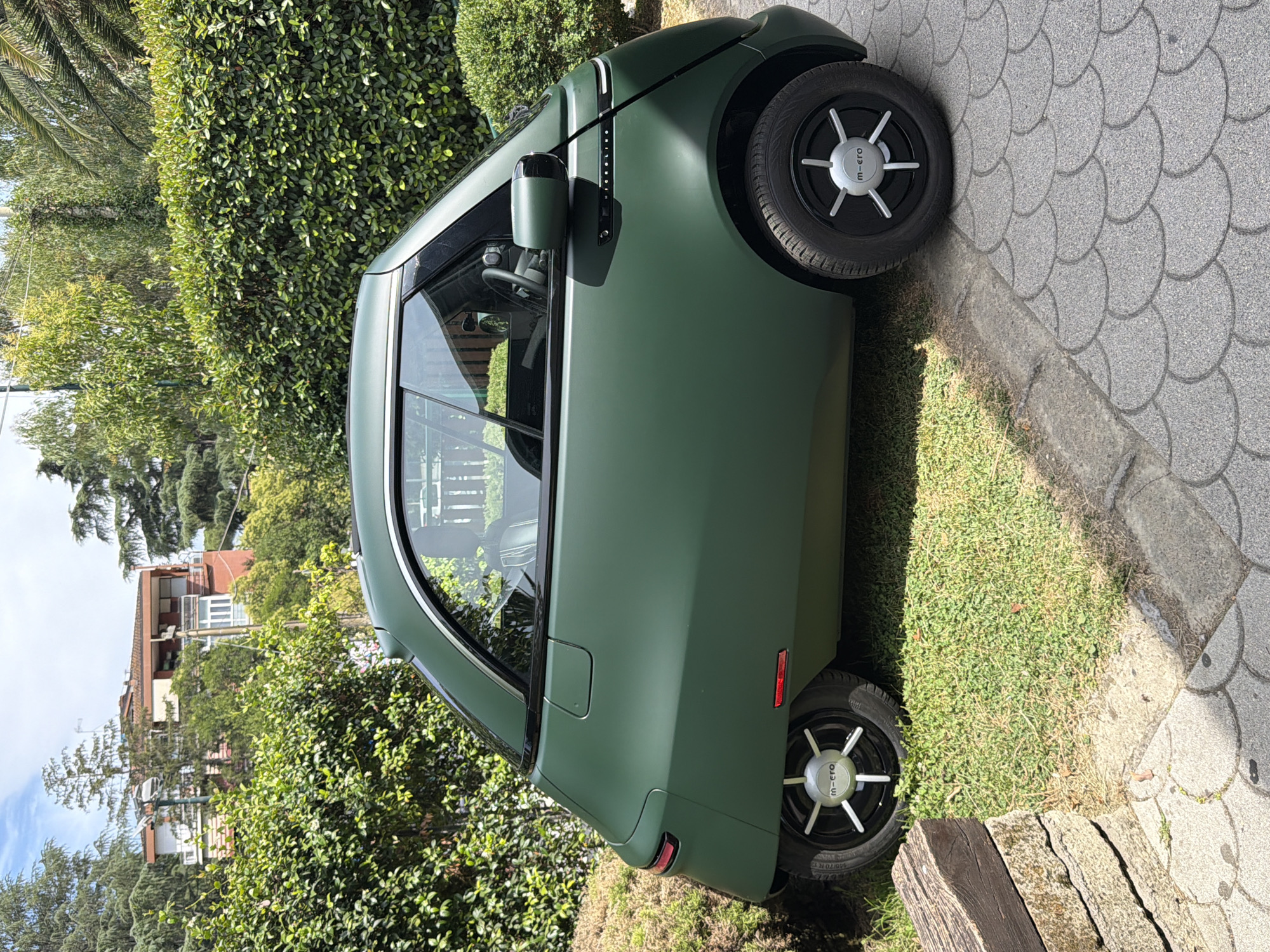 M-cro electric three-wheeler parked along a Rome walkway
