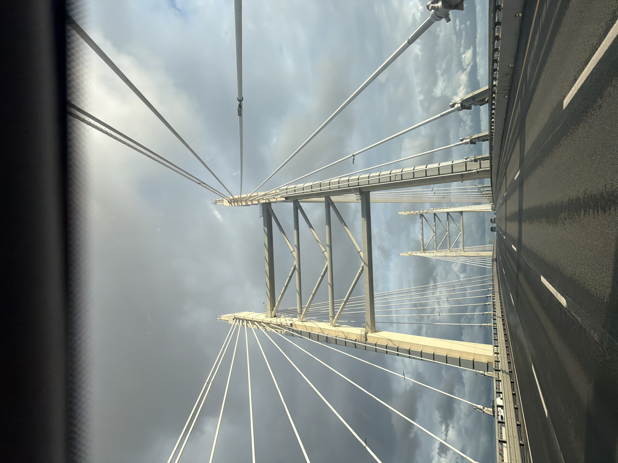 On the road across a cable-stayed bridge under cloudy skies