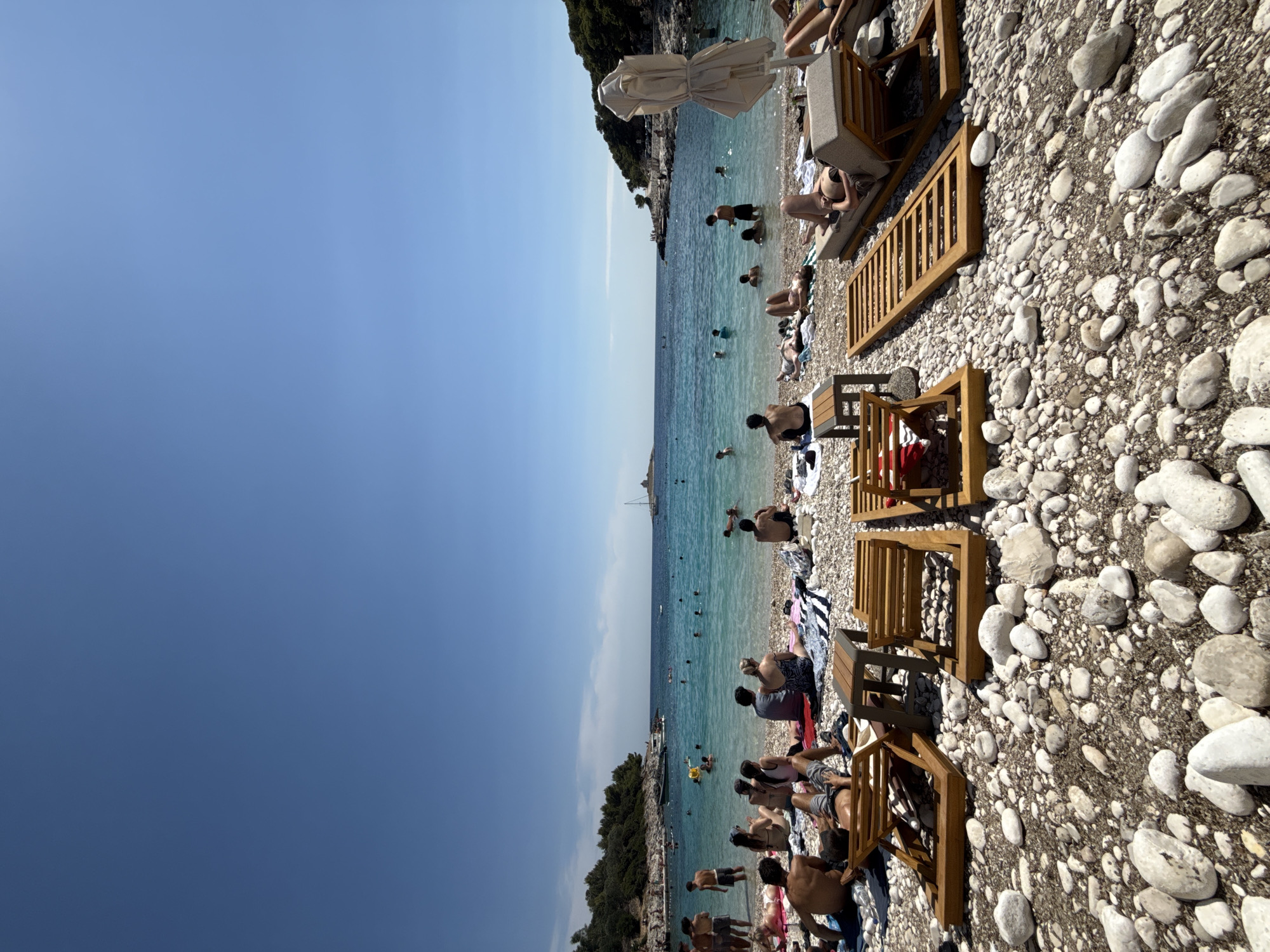 Hvar beach afternoon: swimmers, sailboats, and a lighthouse island