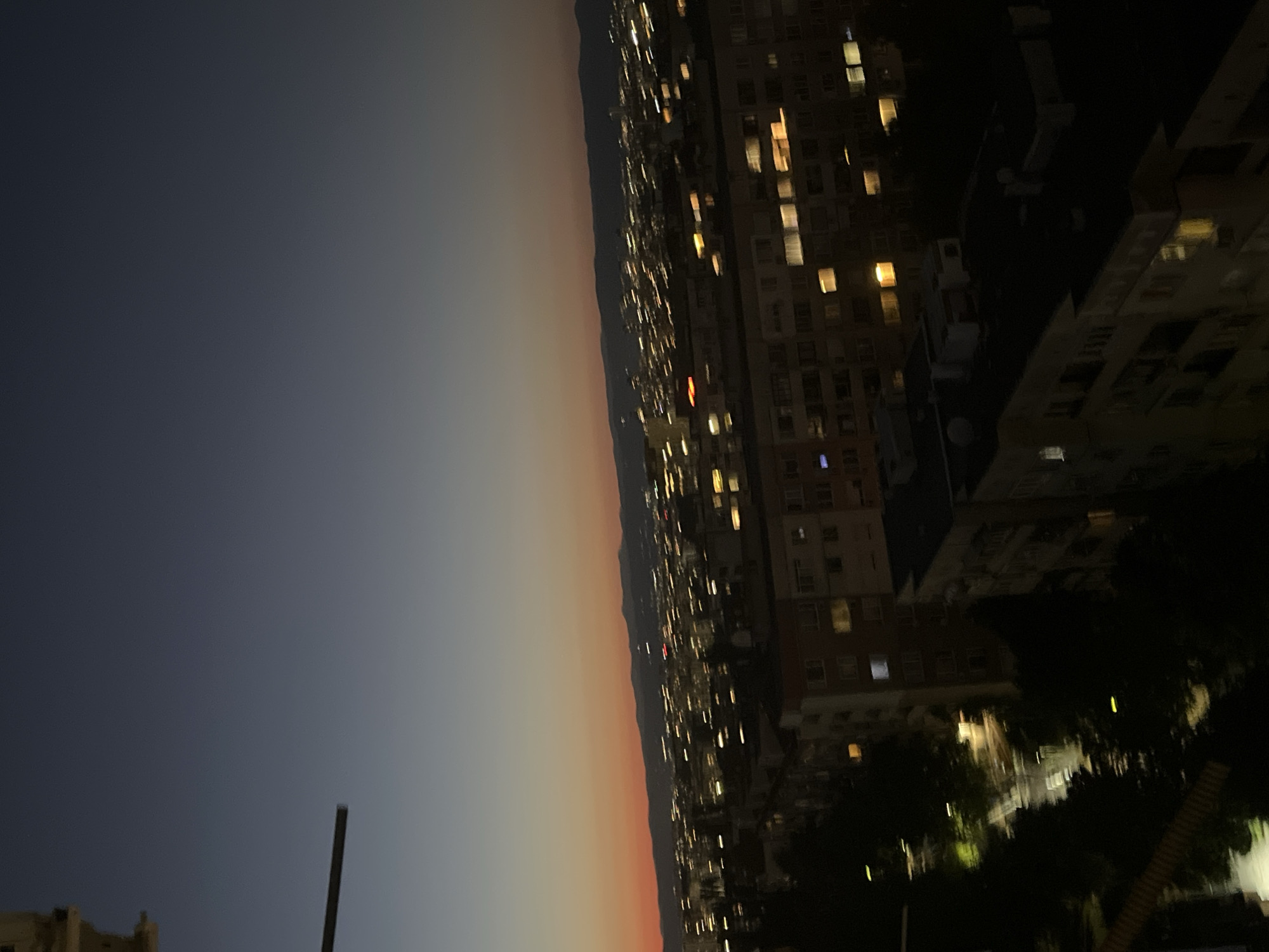 City skyline at dusk, blue-to-orange sky over silhouetted buildings