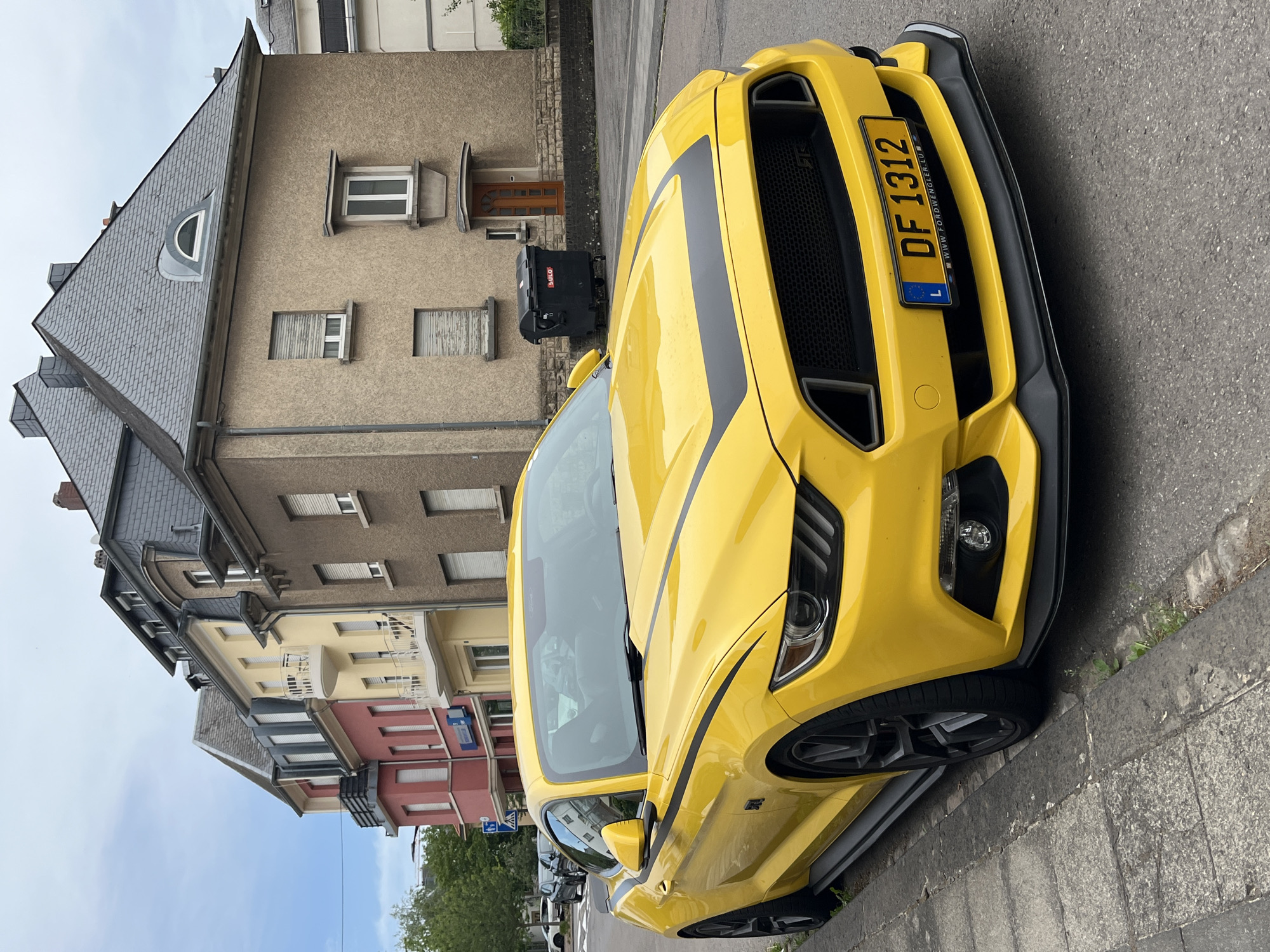 Yellow Ford Mustang with racing stripes parked in Luxembourg City