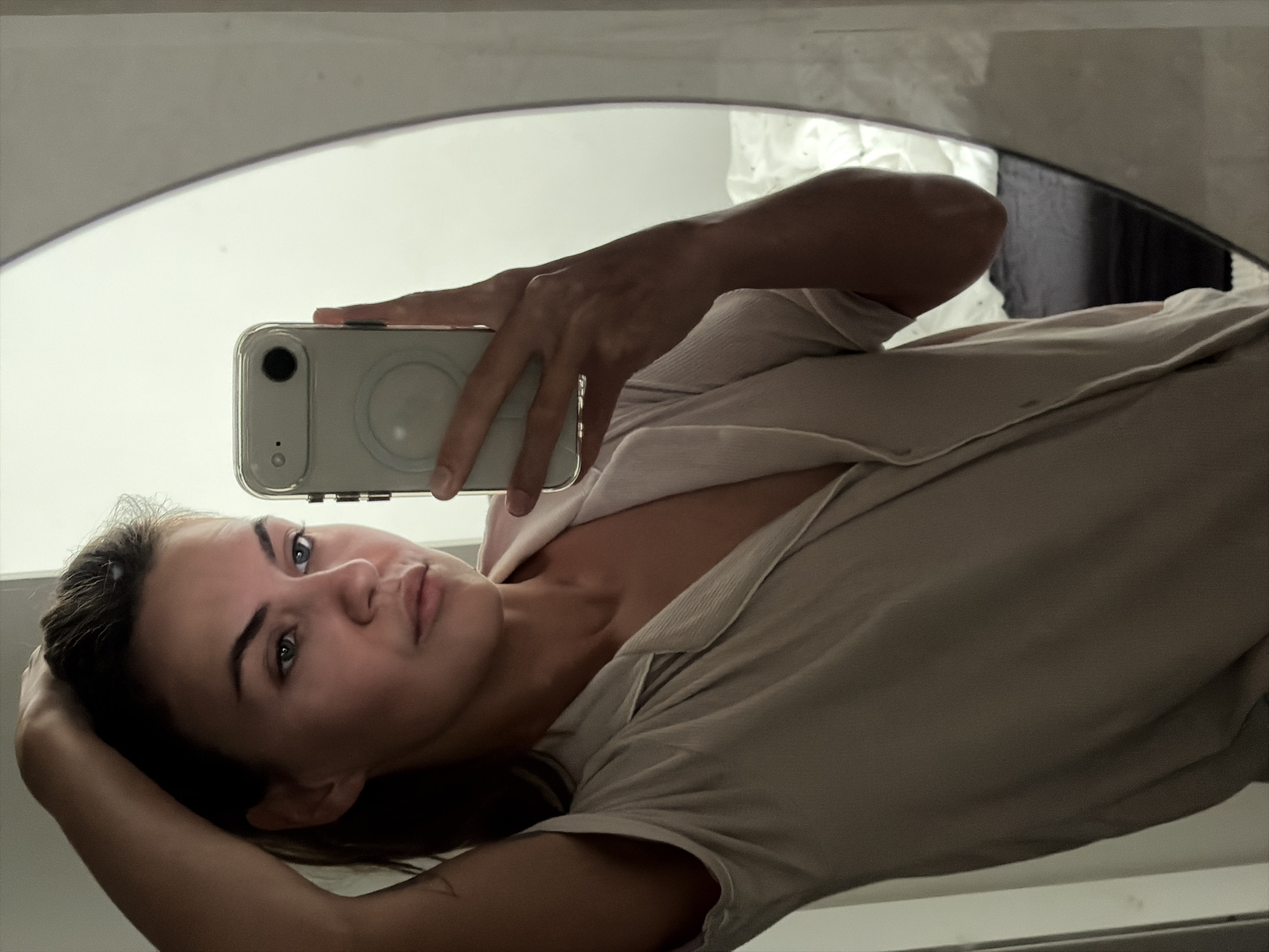 Mirror selfie and skincare bottle in a Holon bedroom