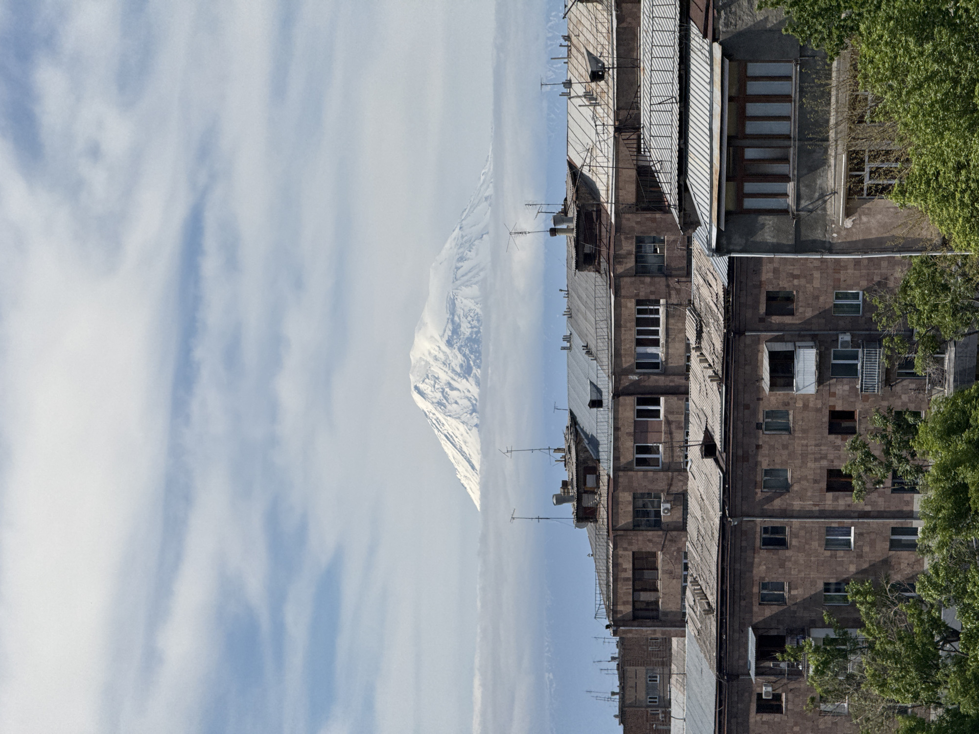 Urban witness captures snow-capped mountain view through clouds