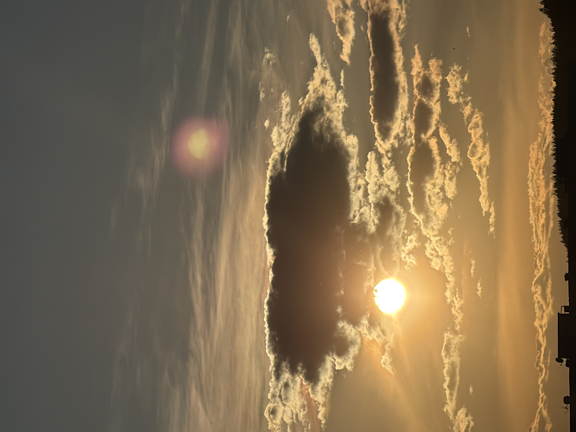 Sun breaks through dark clouds in afternoon sky