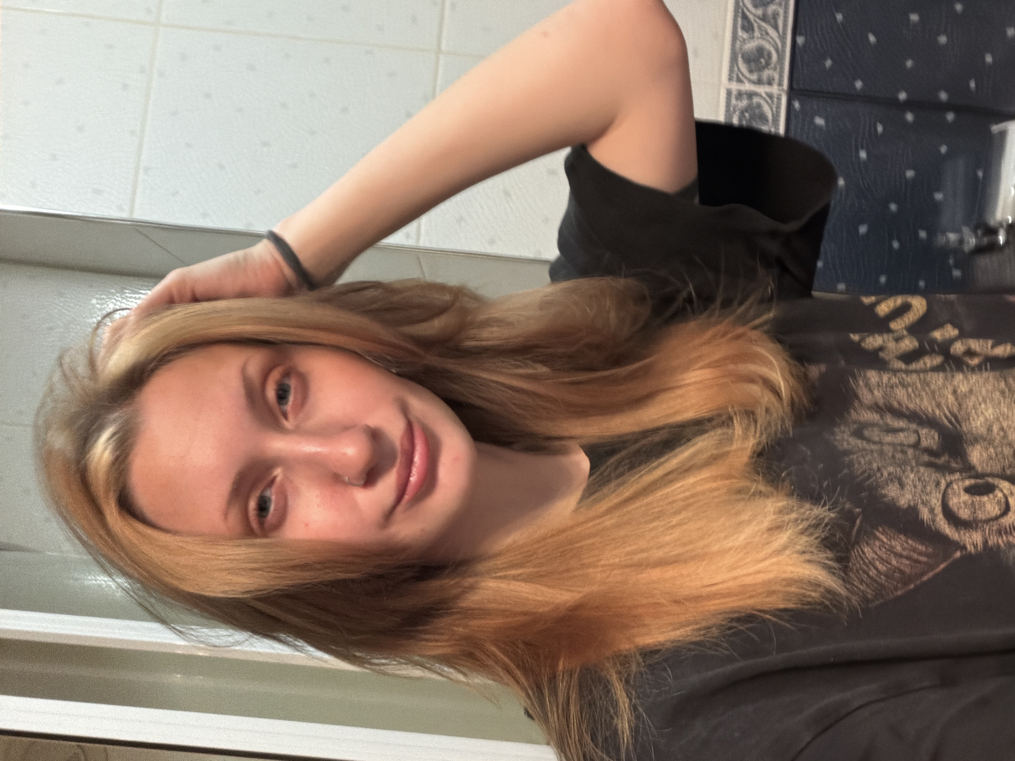 Bathroom mirror selfie session, black graphic tee, orange phone