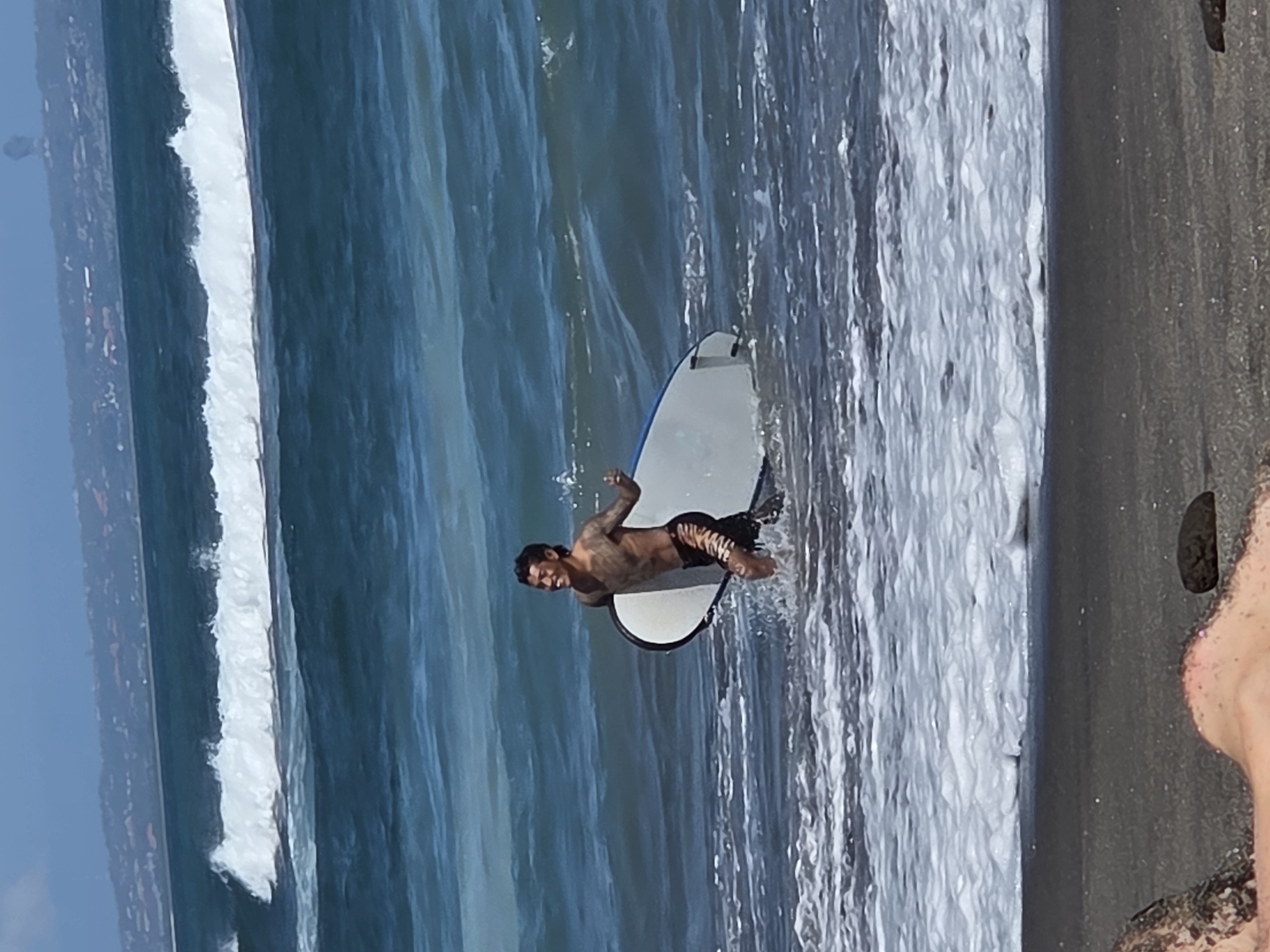 Morning at North Kuta's black sand beach: surfers, families, and shoreline views