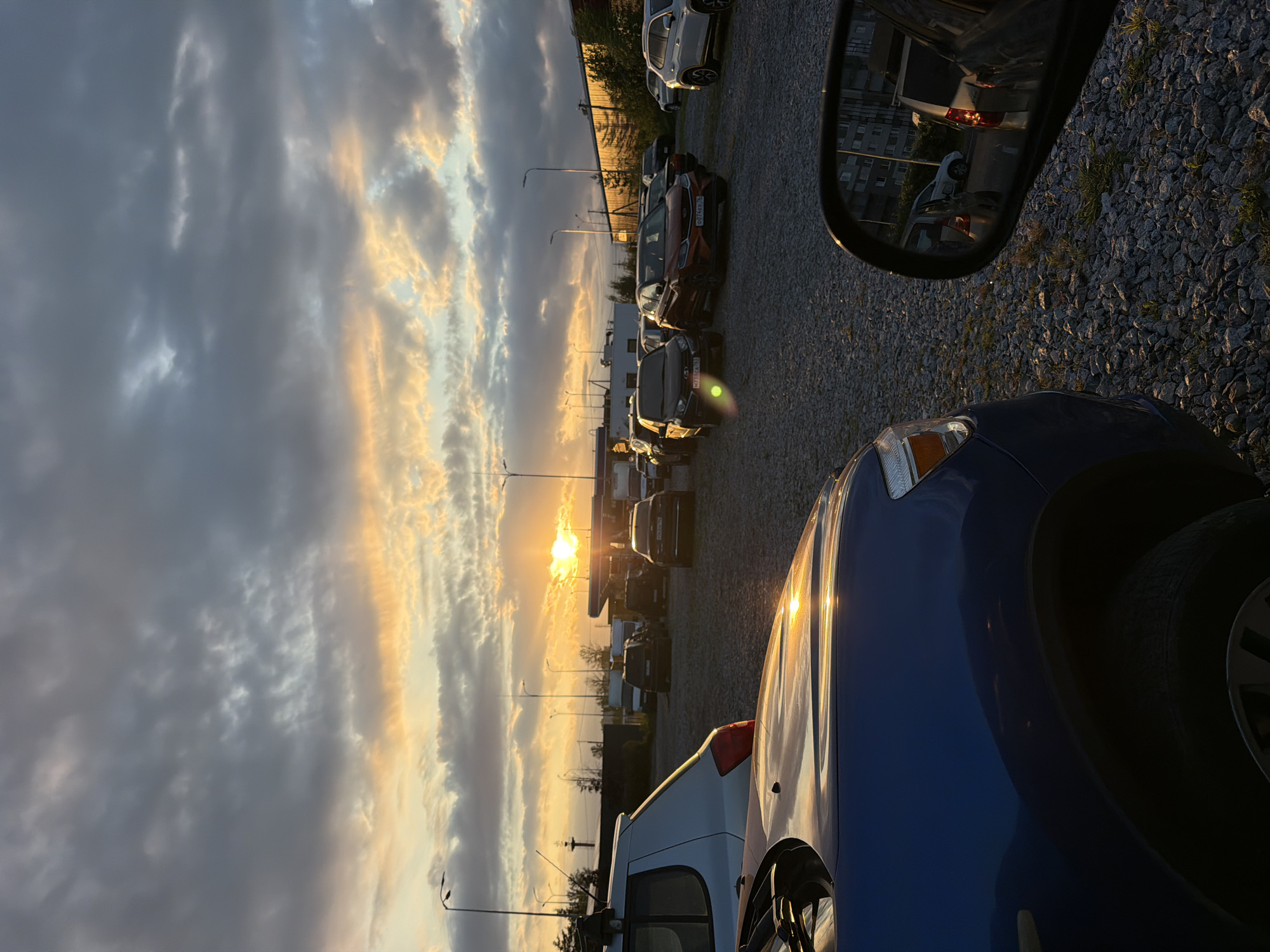 Gravel parking lot glows under a dramatic sunset sky