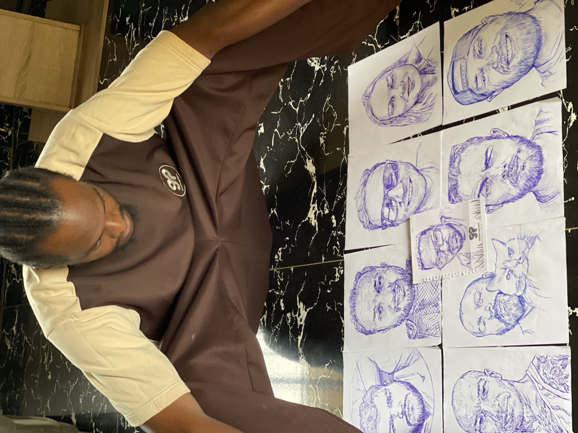 Portrait sketches laid out on a marble floor in Abuja