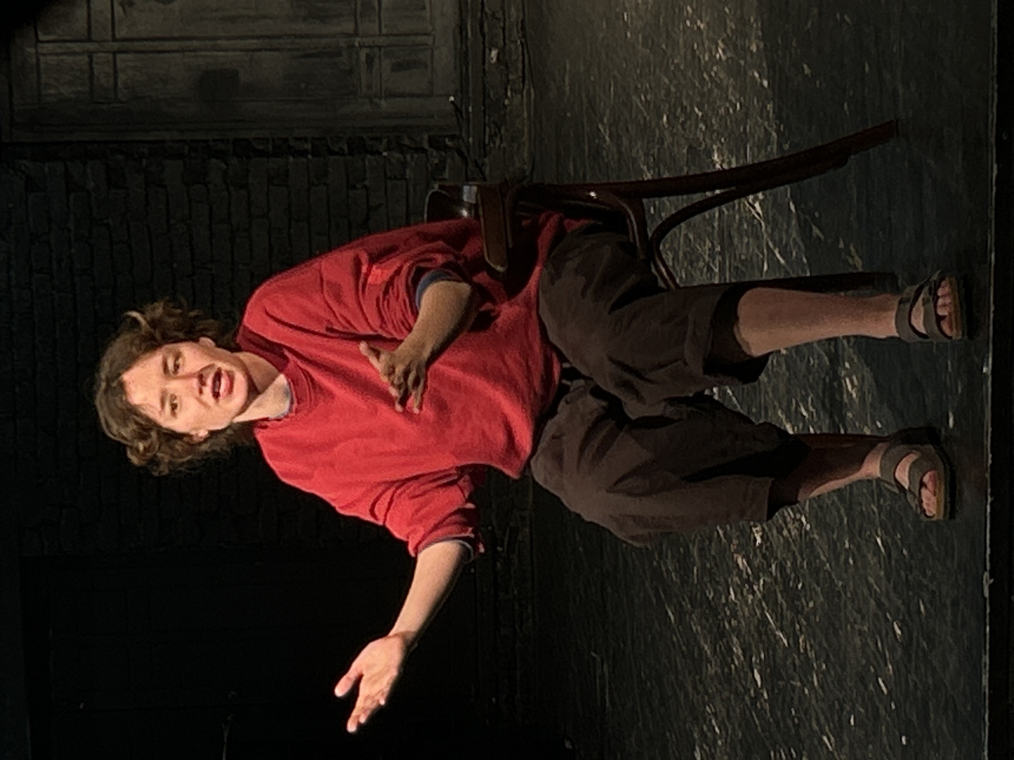 Solo theatrical performance captured on intimate brick-walled stage
