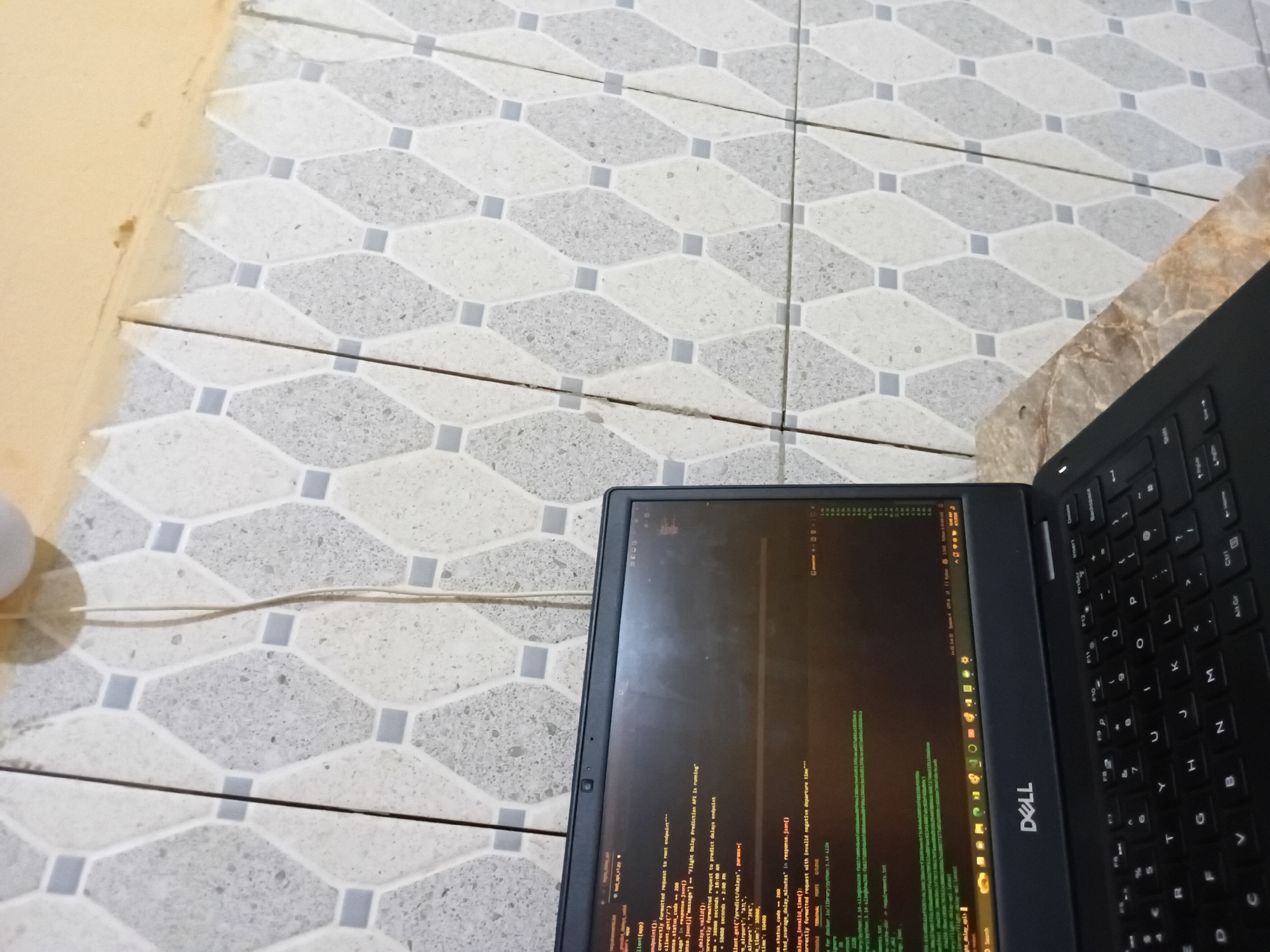 Dell laptop shows flight delay prediction code on floor