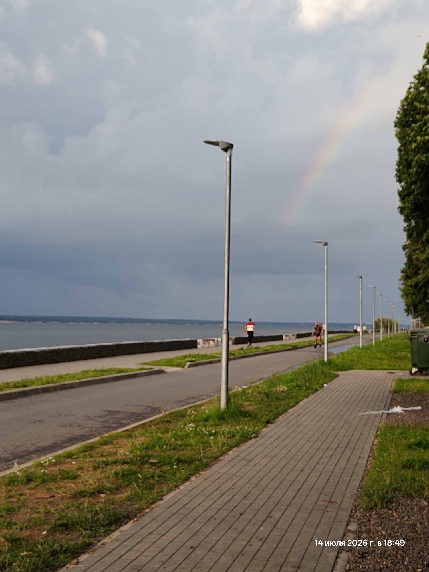 Stormy sunset walk along a waterfront promenade with rainbow