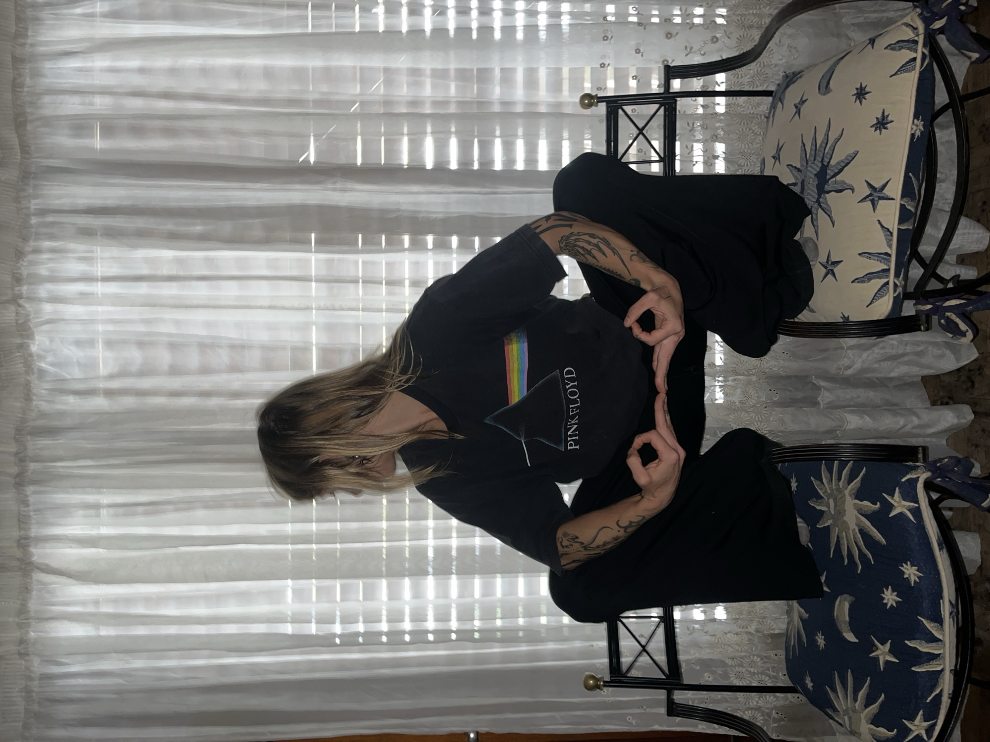 Person in Pink Floyd shirt makes OK gesture by window
