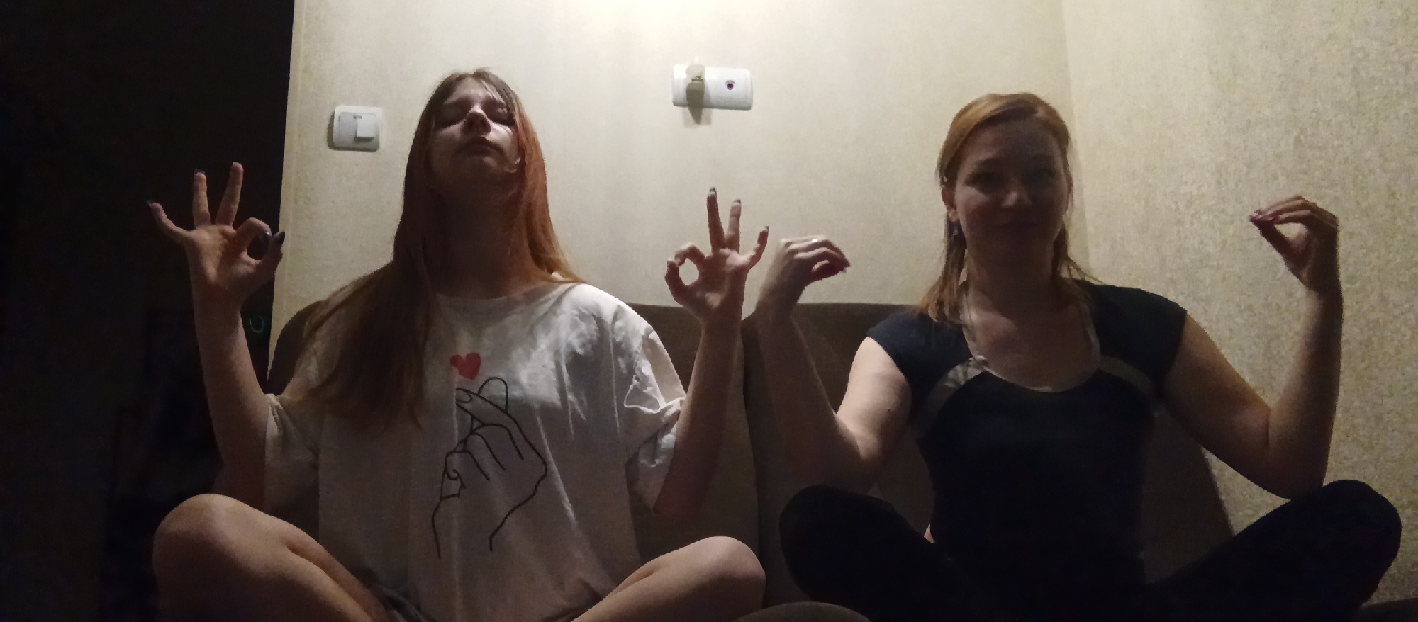 Two women sit together on brown couch indoors