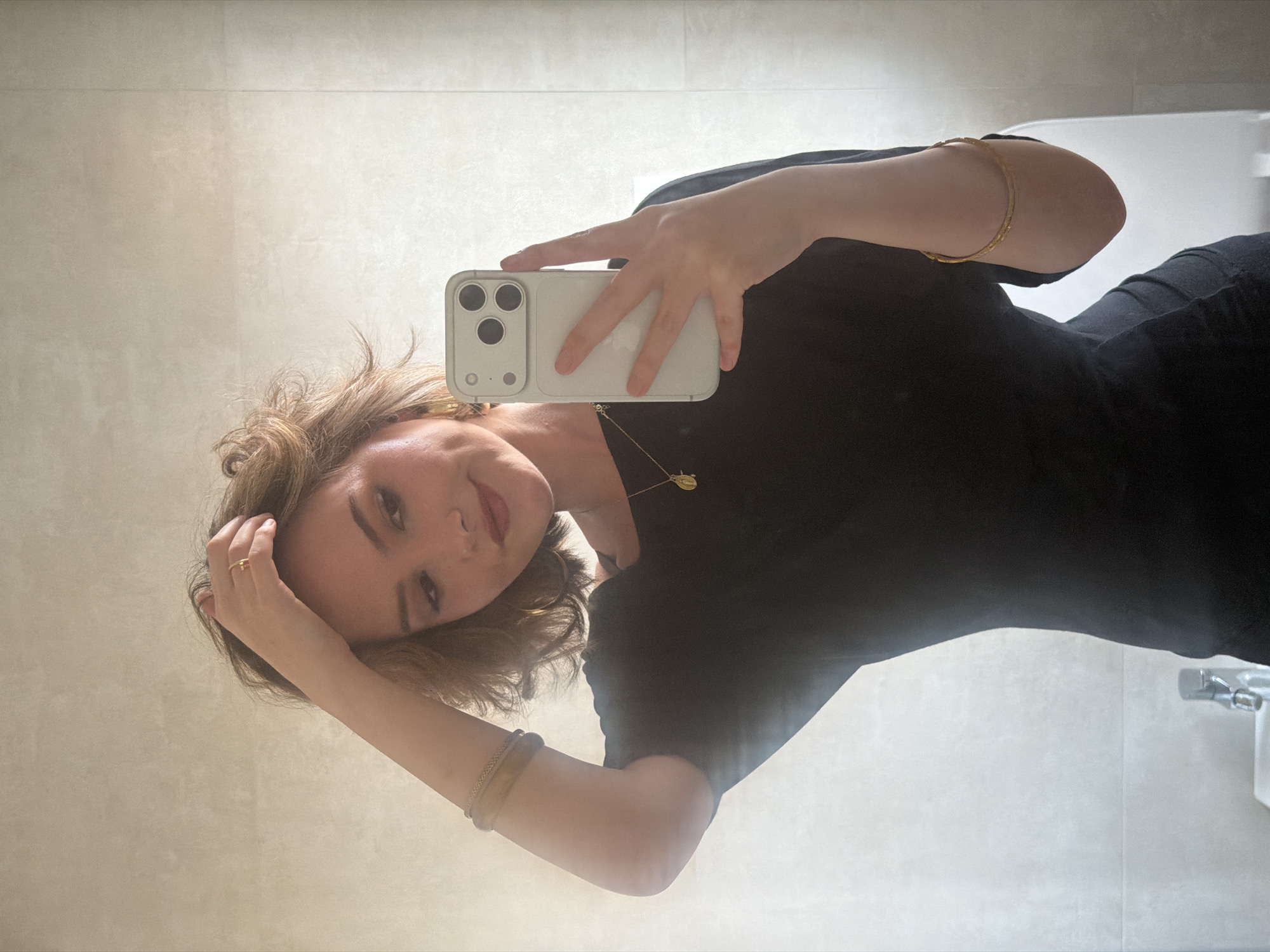 Woman takes bathroom selfie in Milan wearing black dress