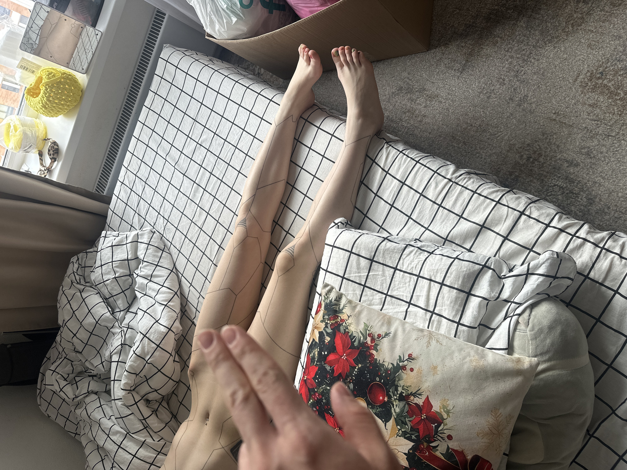 Person with geometric tattoos rests on checkered bed in Lyubertsy