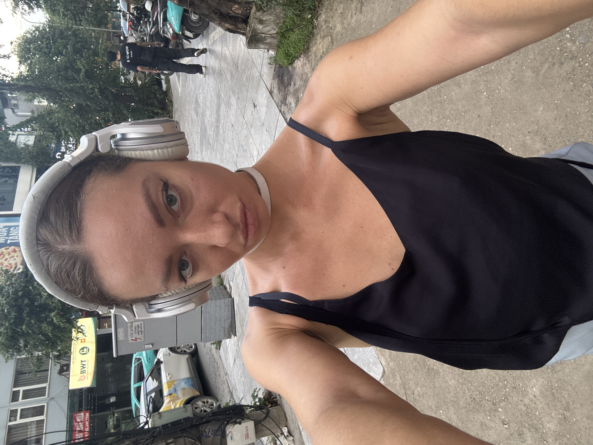Hanoi street corner: retail signage, VinFast EVs, everyday city life