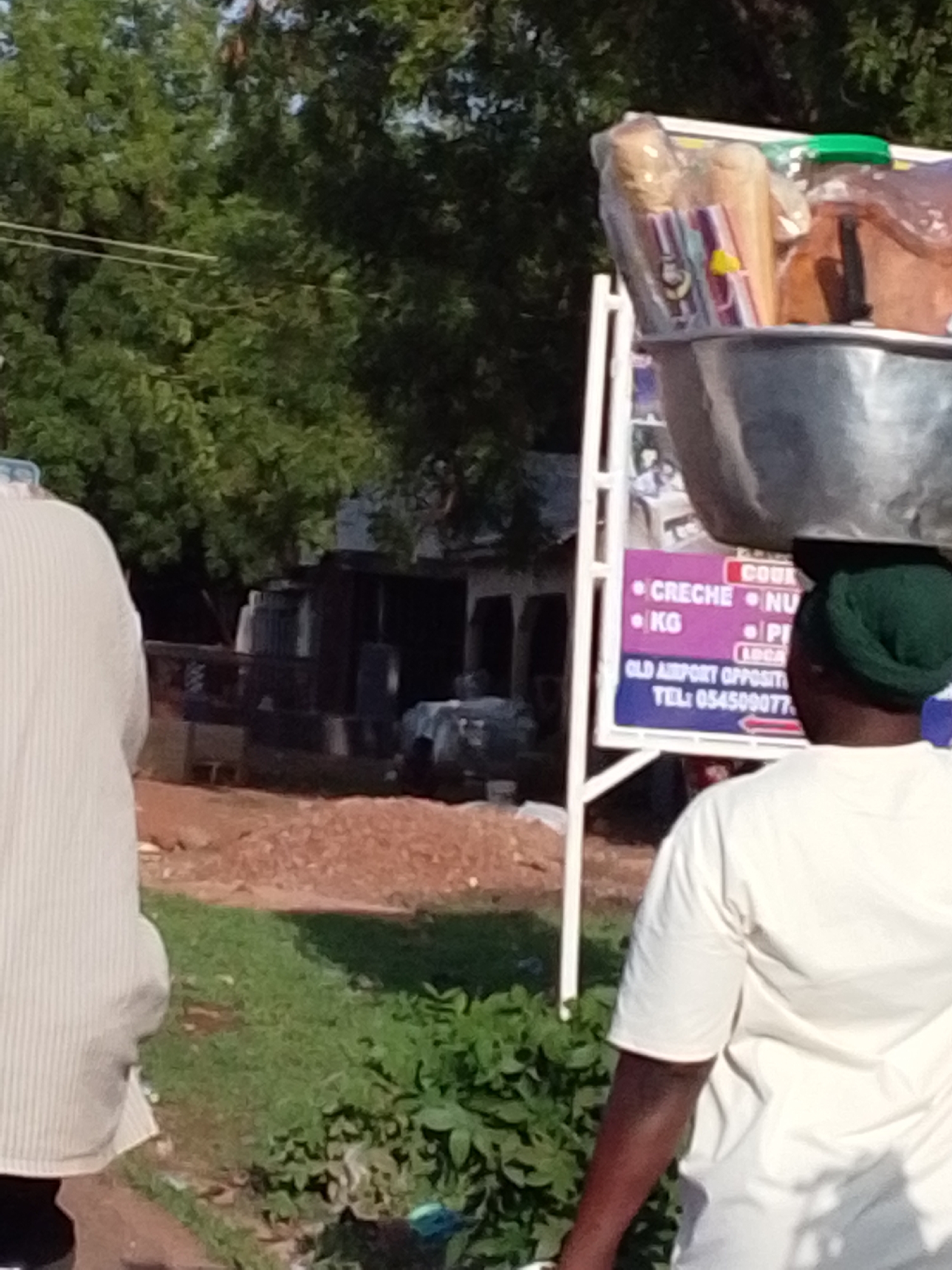 Person carries head load through dusty Tamale streets