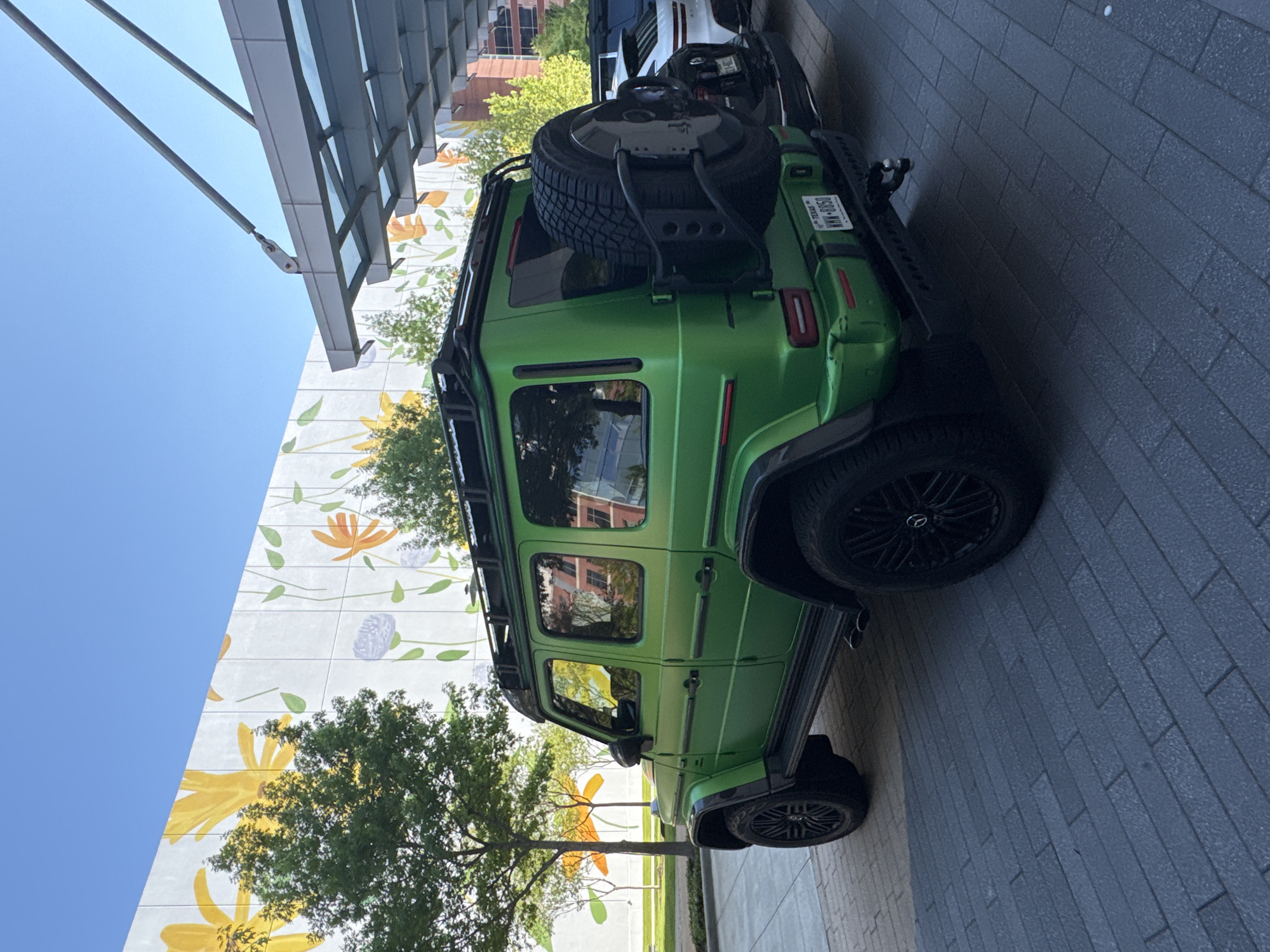 Lime-green G-Wagon spotted on brick walkway near colorful mural