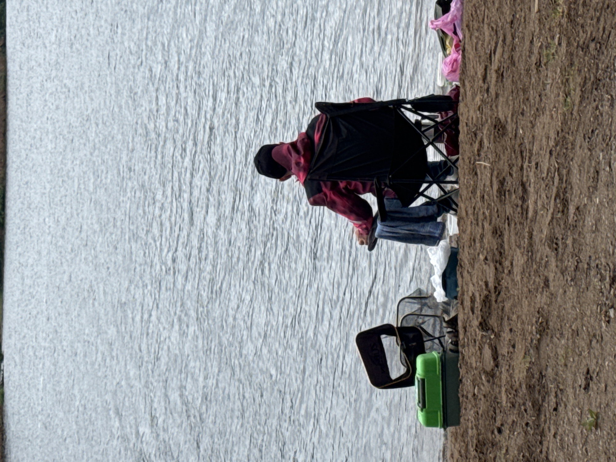 Person sits by industrial waterfront in Chaikovsky, Russia dawn