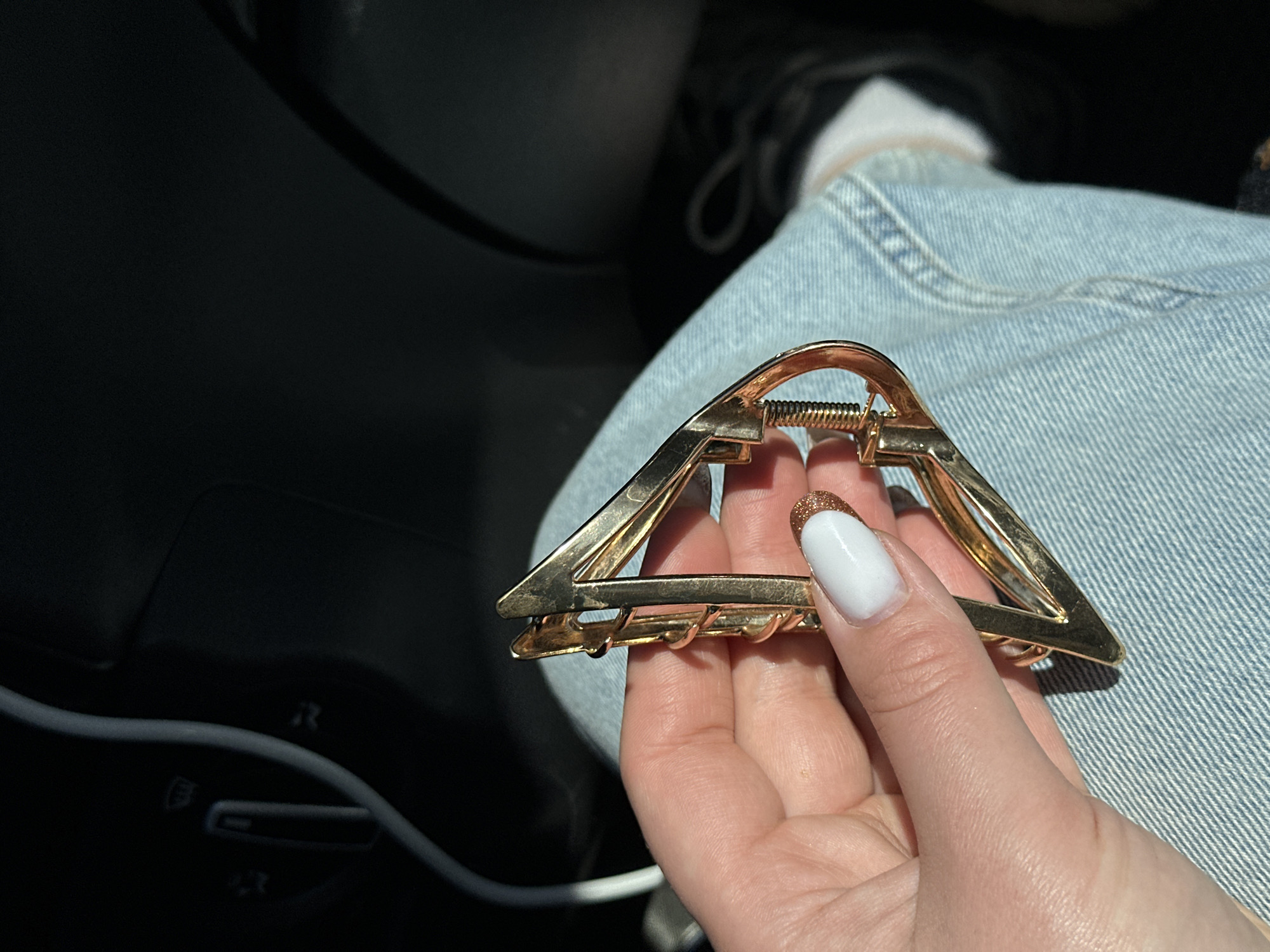 Person holds gold hair clip inside car in Russia