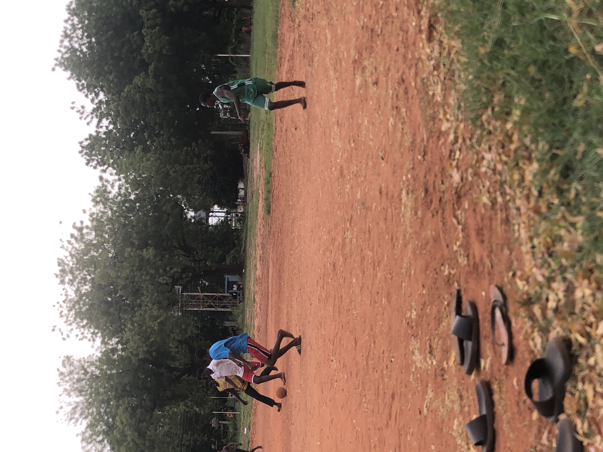 Young men play casual soccer on dirt field in Nigeria