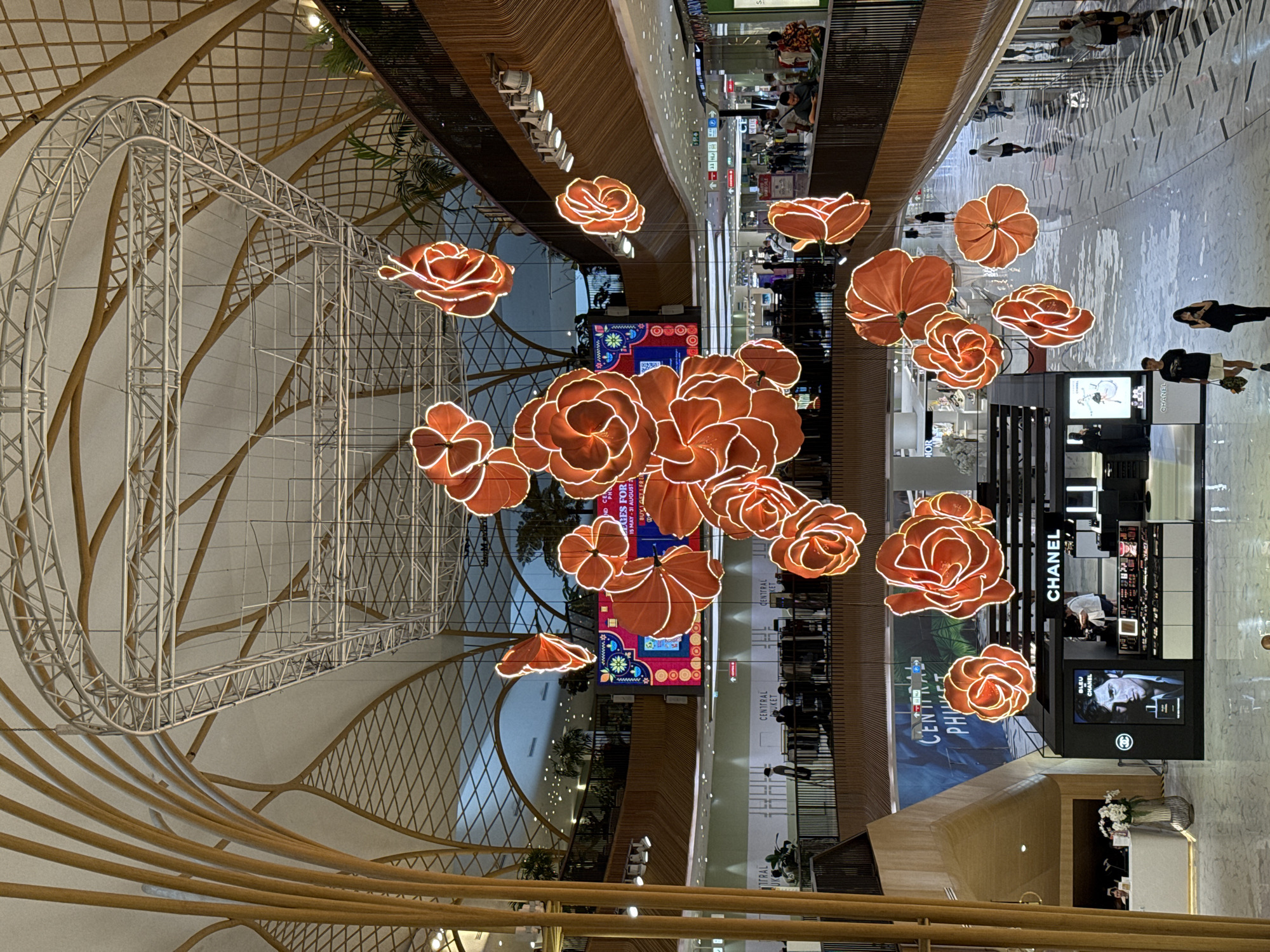 Inside a Wichit mall with flower light installations and retail stops