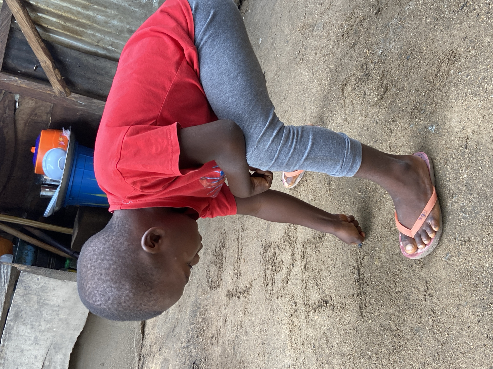 Child draws in dirt with stick in Mararaba, Nigeria