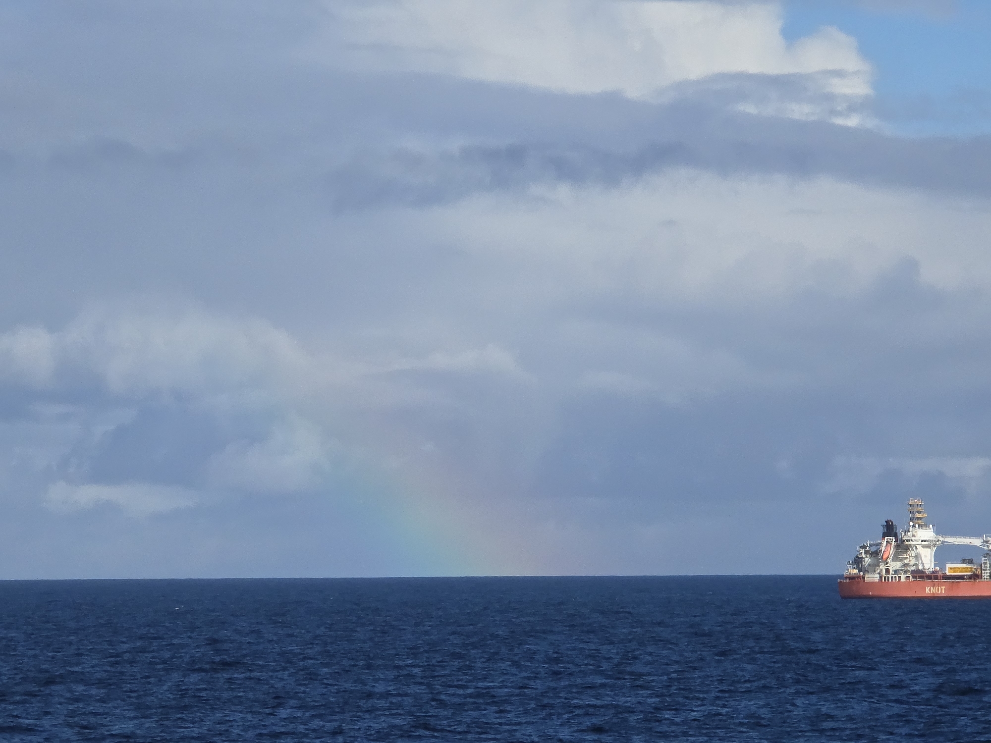 Rainbow appears over Norwegian waters as vessel navigates coastline