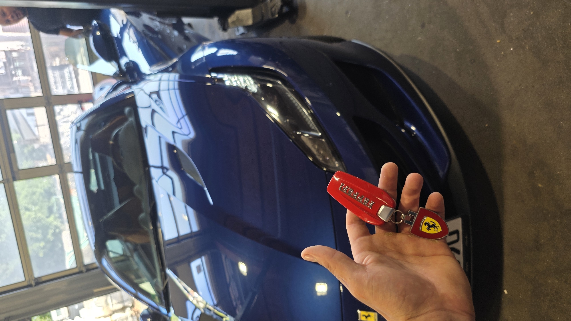 Blue Ferrari gets workshop attention alongside a black BMW SUV.