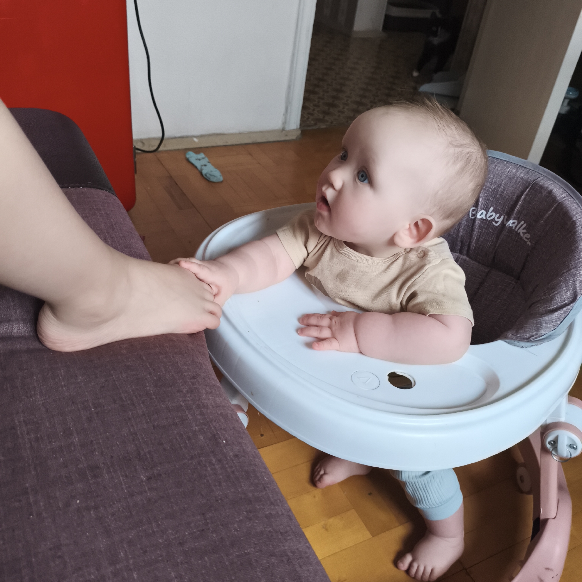 Infant in walker interacts with seated person
