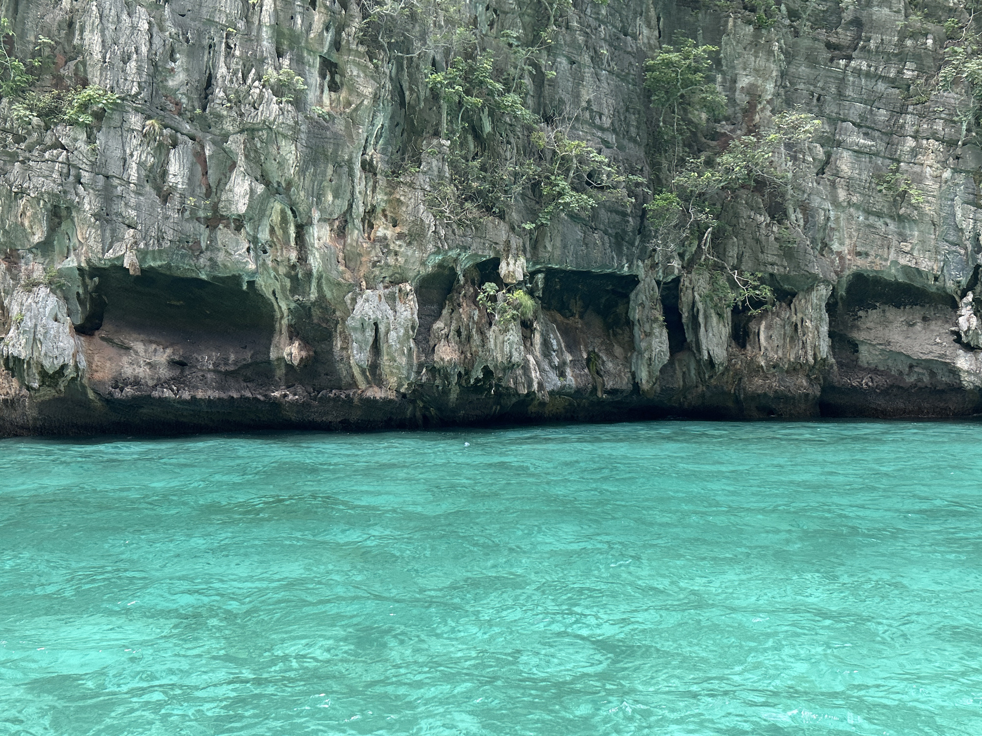 Long-tail boat drifts past limestone cliffs in Haad Yao
