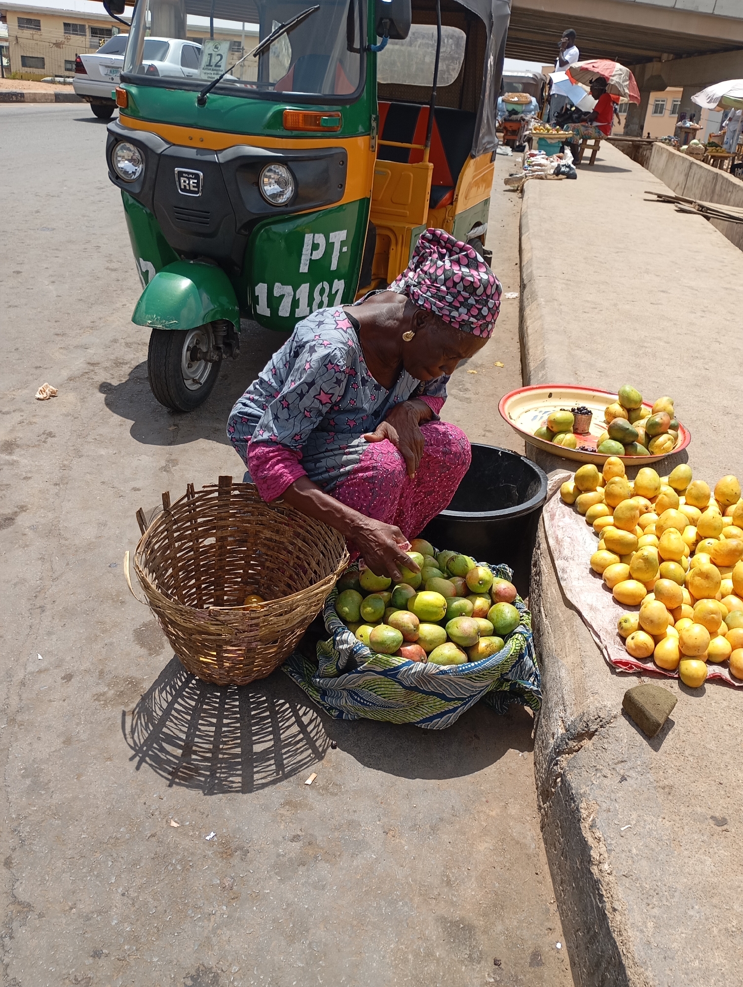 Elderly woman sorts mangoes curbside in Jos, Nigeria